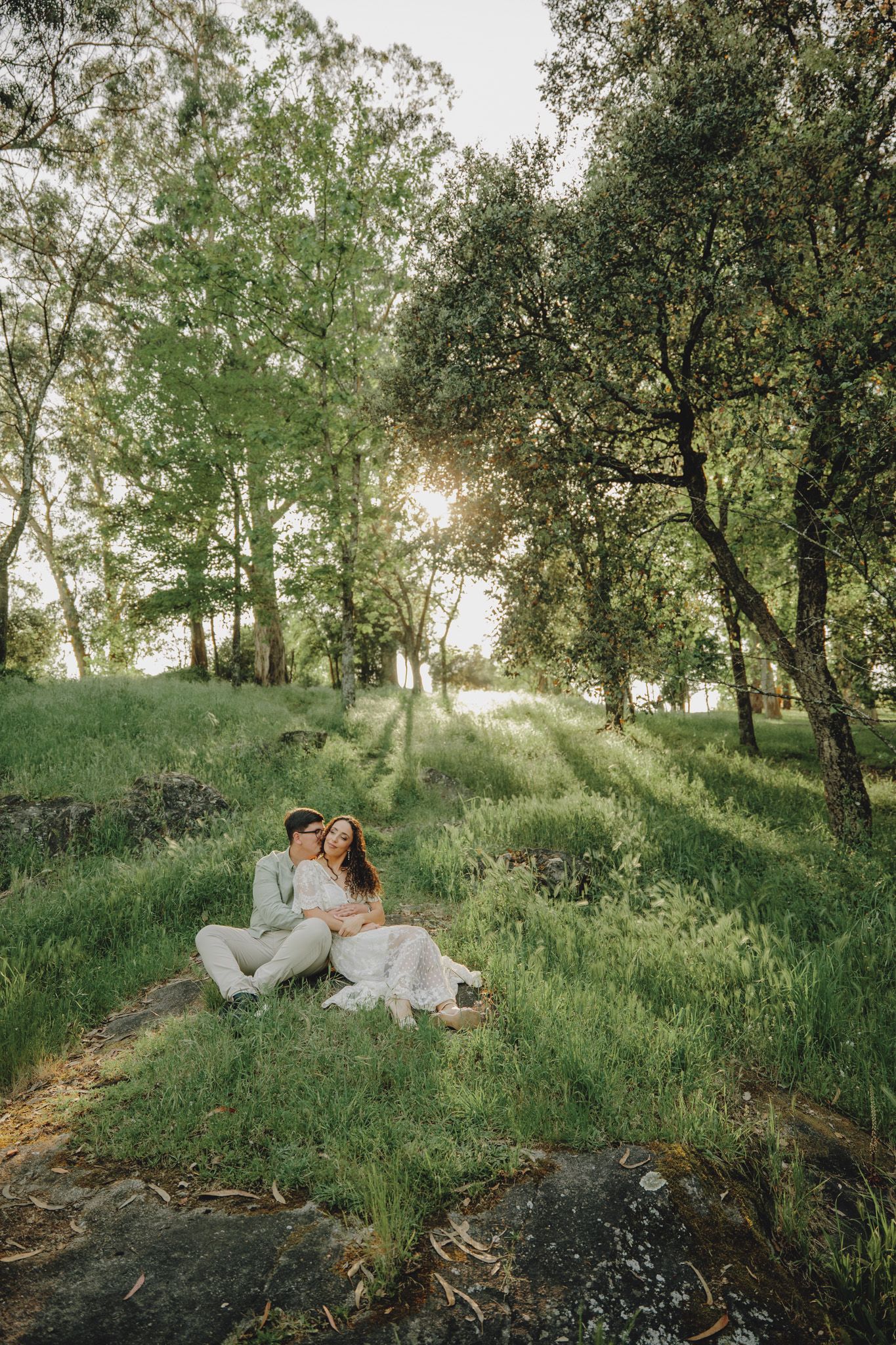 A romantic sunset photoshoot in a lush green field with olive trees creating a dreamy atmosphere.