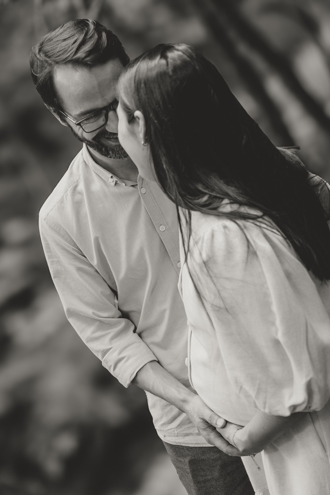 Black and white romantic portrait of a couple in white shirts sharing an intimate moment together outdoors.
