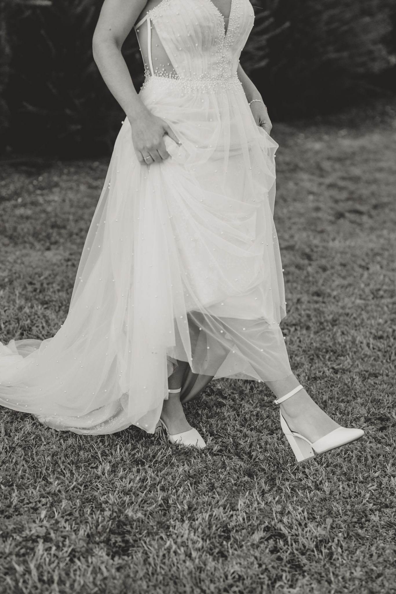 Close-up shots of a bride's dress and shoes as she moves across grass.