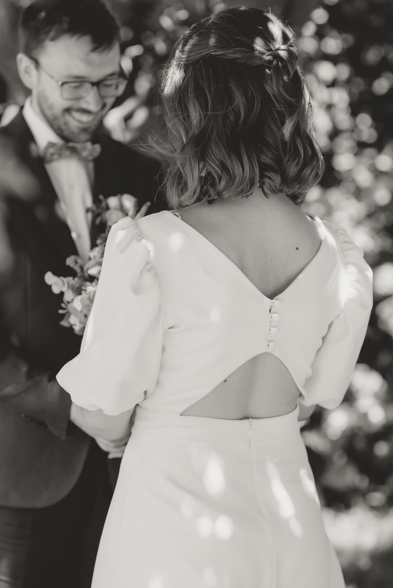 Close-up details of a white wedding dress and veil with bokeh lights in the background.