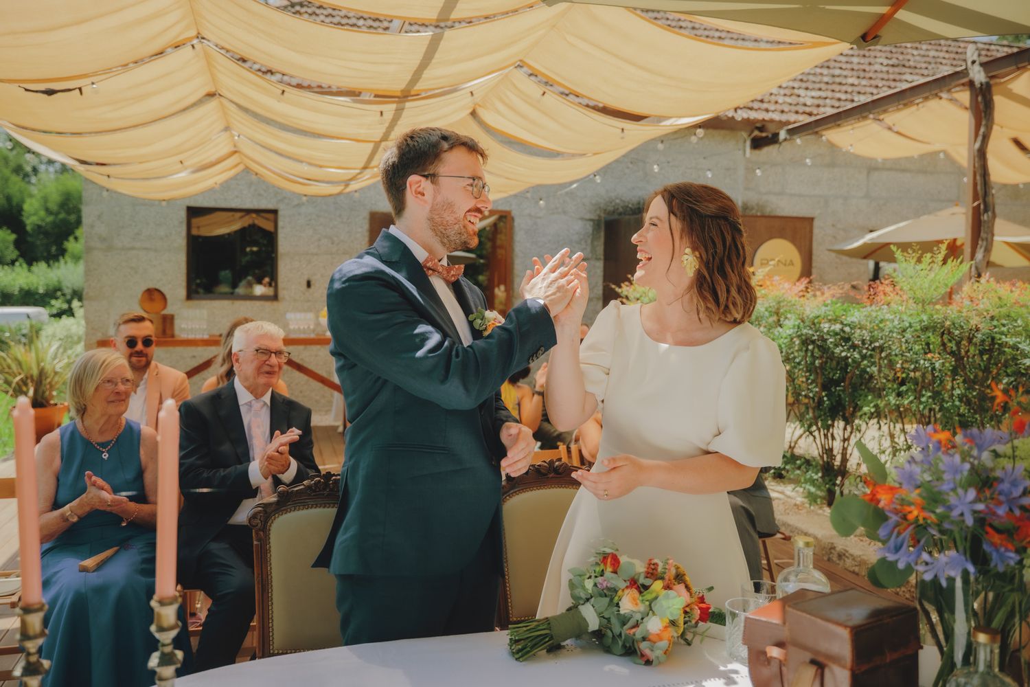 Guests celebrate at an outdoor wedding reception under an elegant white tent canopy.