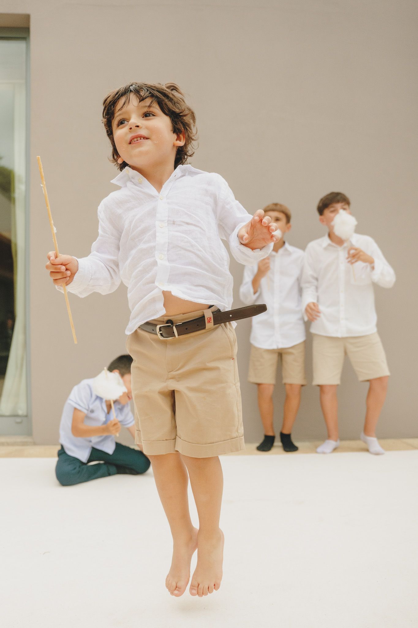 Children in matching formal wear playing and jumping on light colored background.