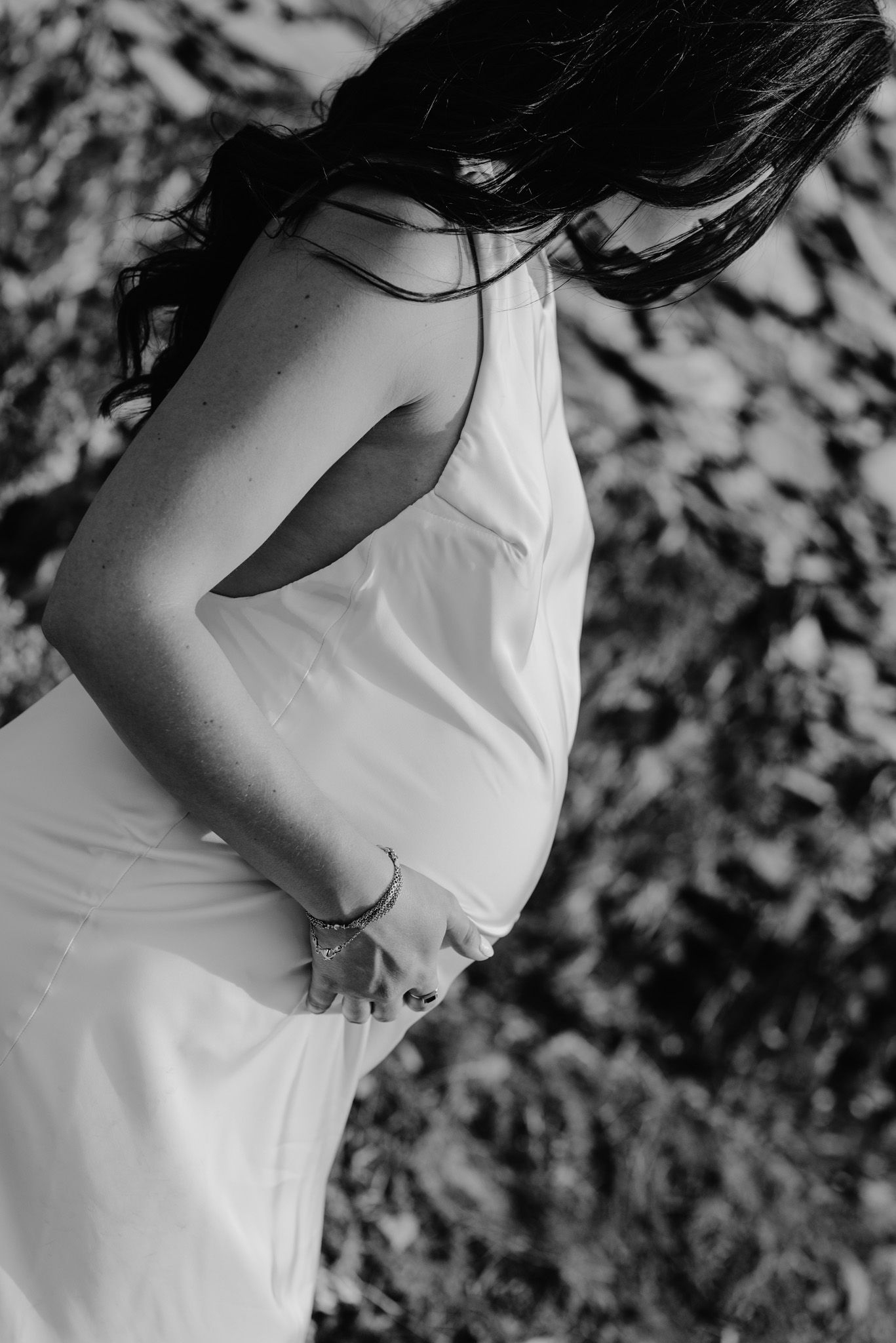 Artistic black and white close-up shots of someone wearing a white dress against natural textures.