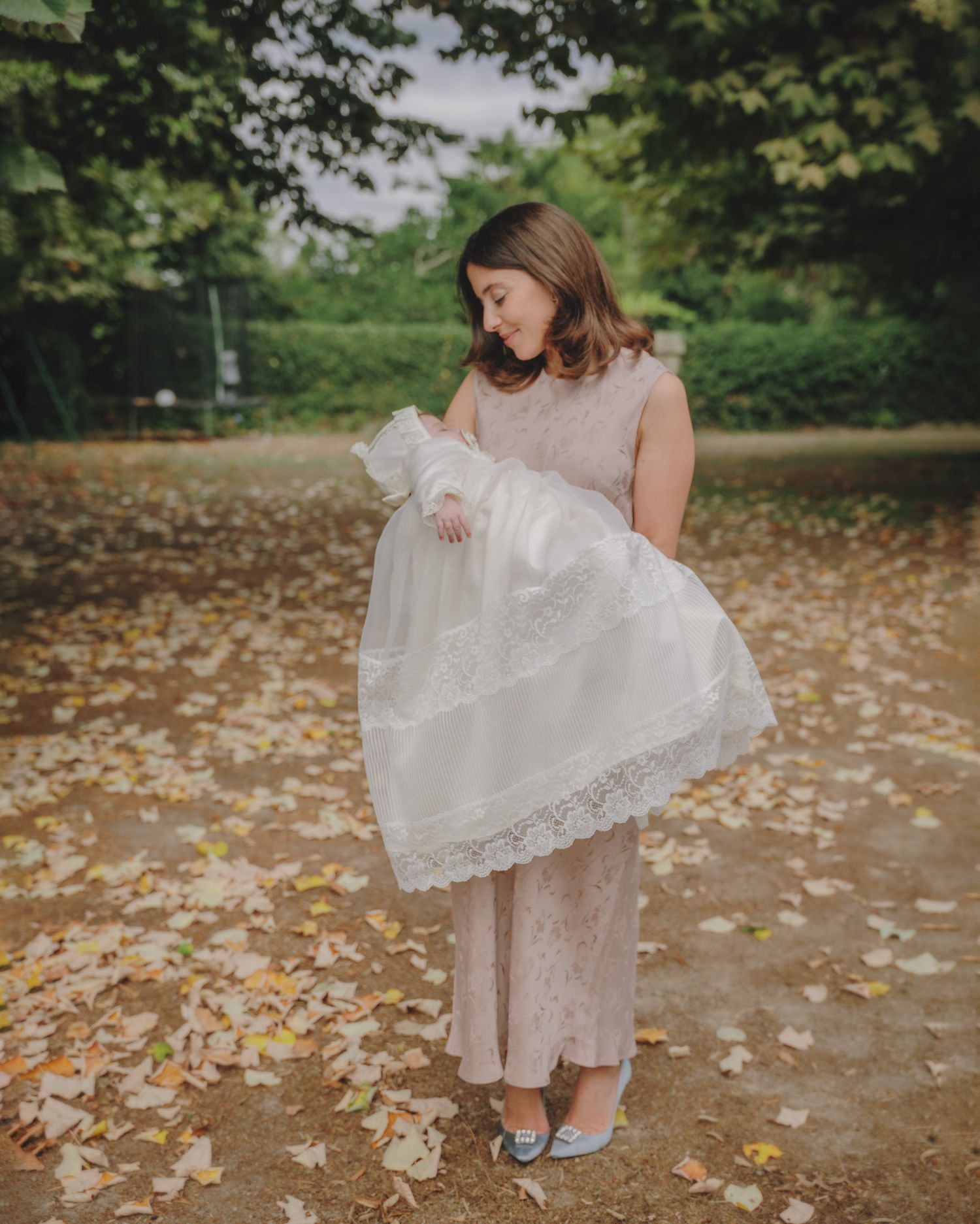 White lace dress details photographed against fallen autumn leaves on the ground.
