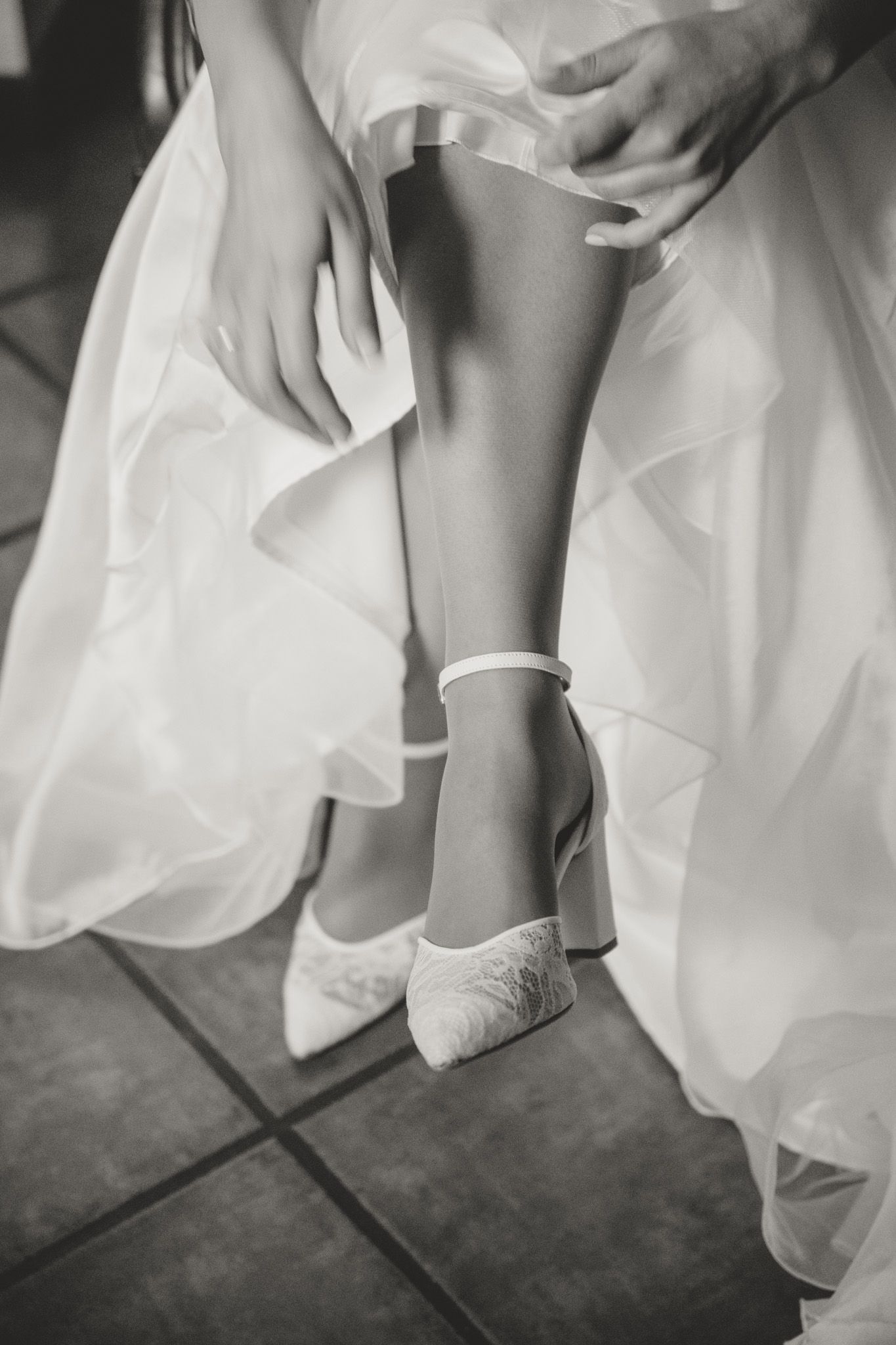 Close-up shots of white dress fabric and shoes against a dark floor.