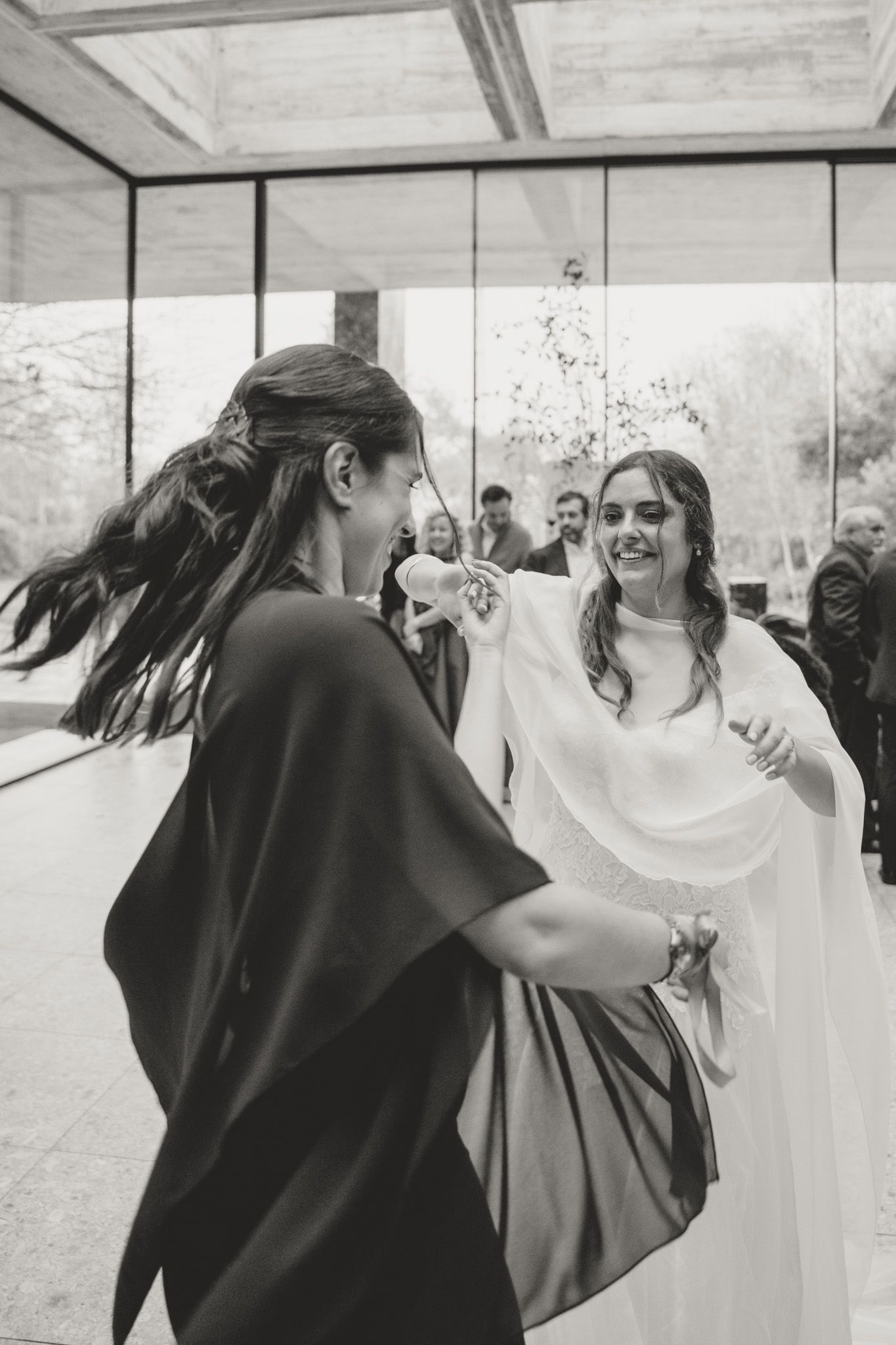 Wedding party celebrates joyfully in black and white formal attire at an indoor venue.