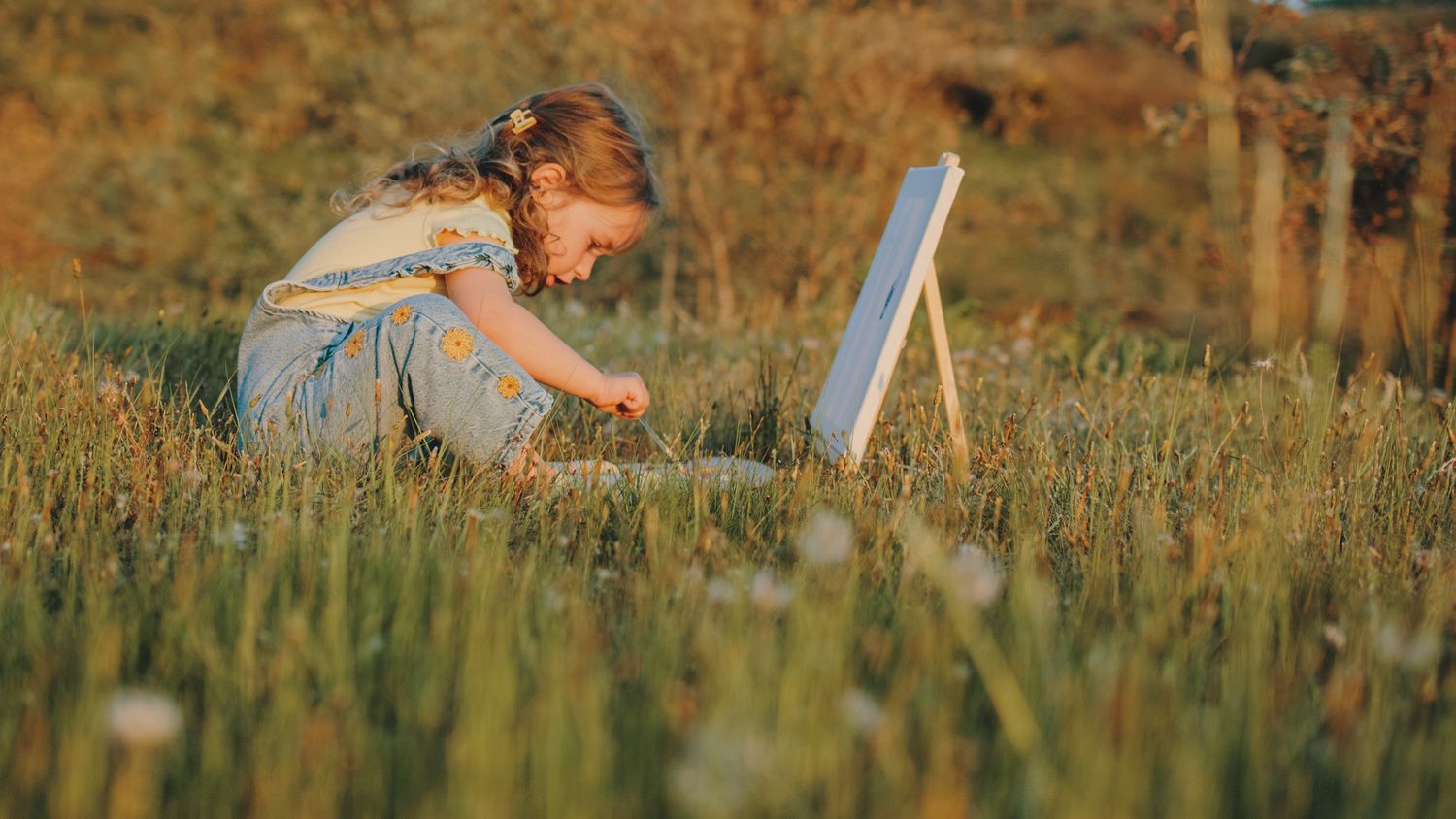 A rustic wooden palette sits in tall grass during sunset.