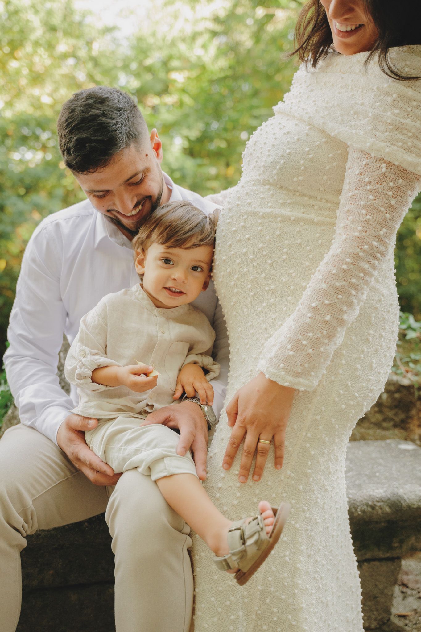 A candid family moment during an outdoor maternity photoshoot with natural lighting.