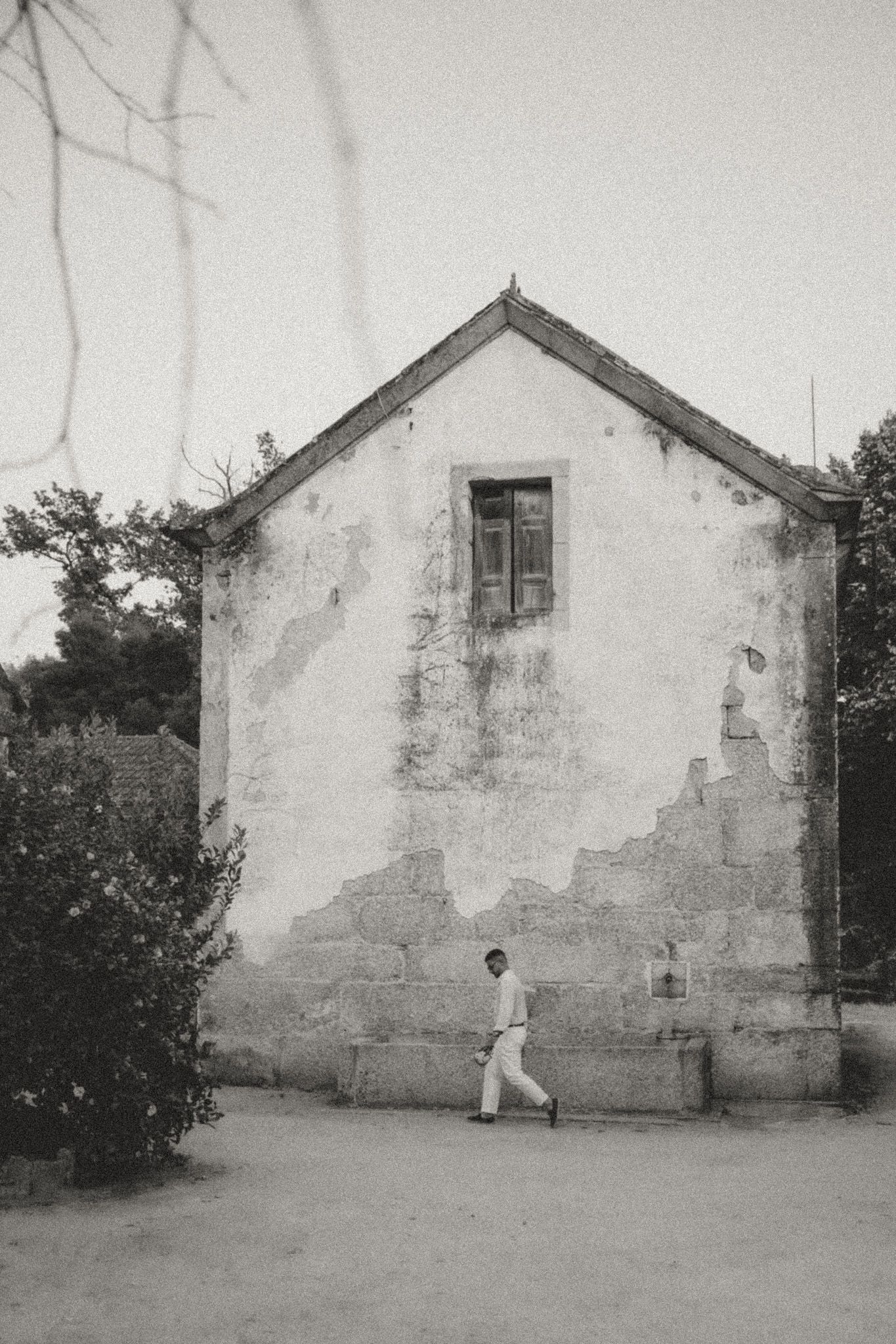 A sequence of artistic black and white photos showing figures against a weathered white building wall.