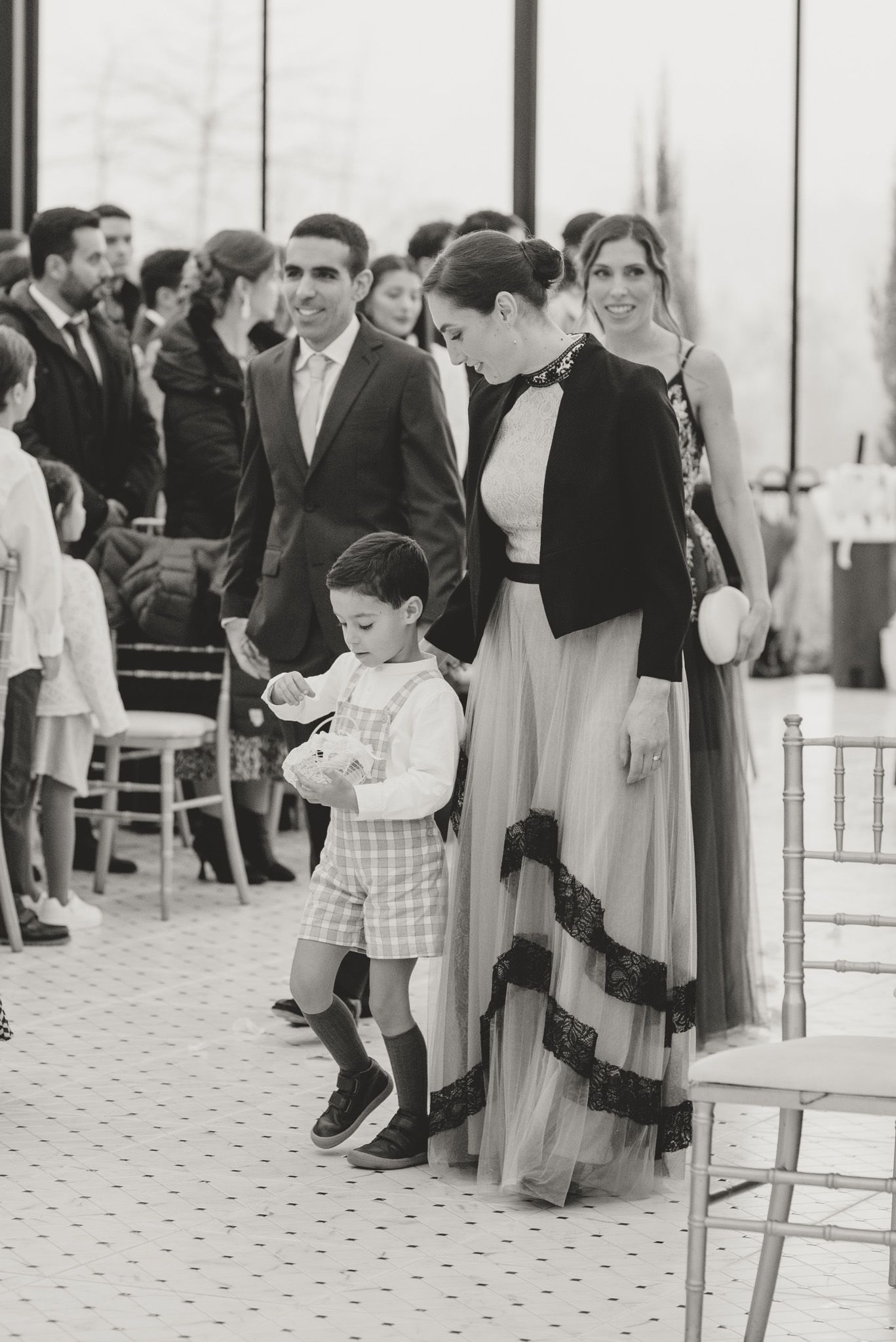 A young child in a plaid shirt plays near chairs during a wedding ceremony.