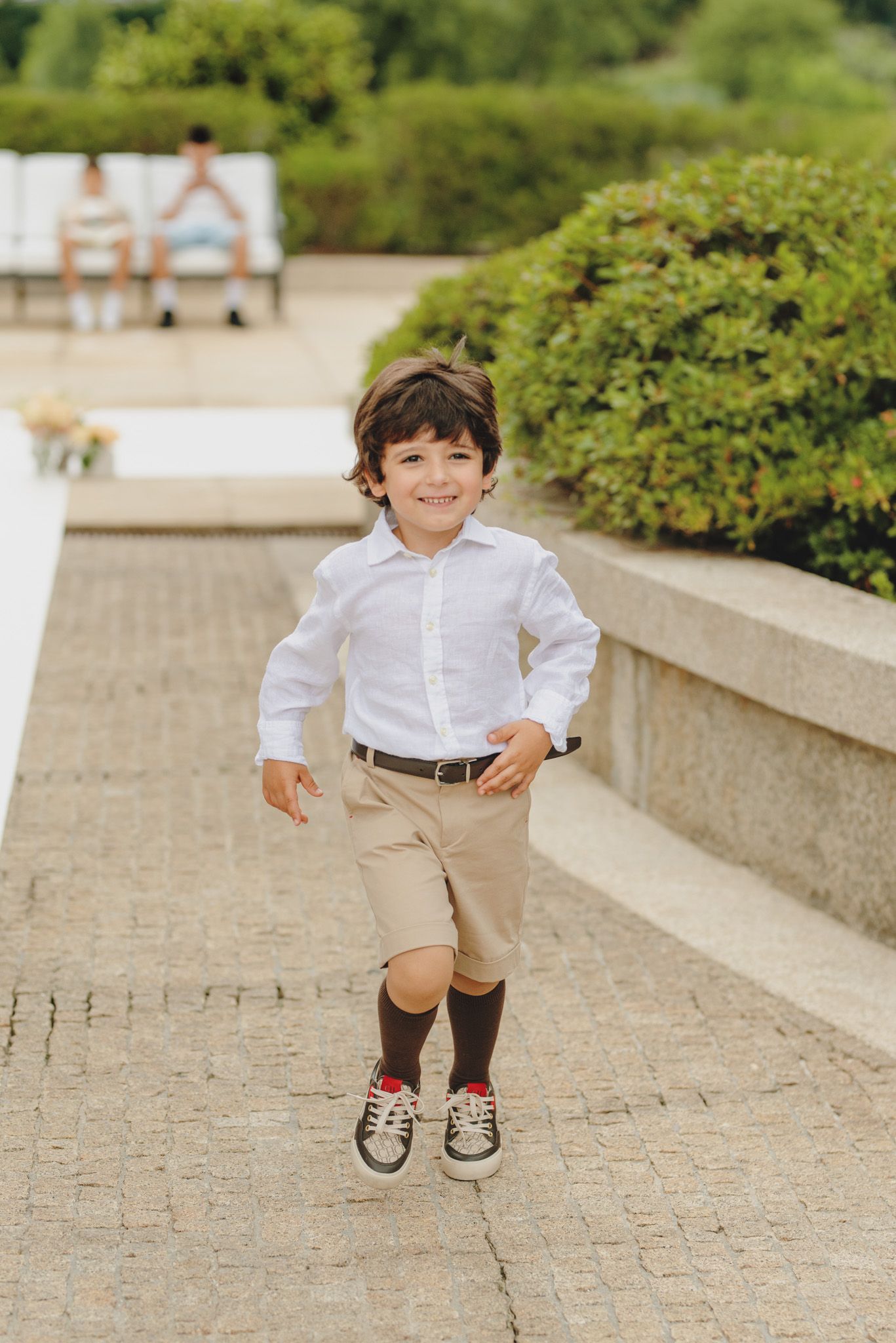 Playful jumping sequence photos on a stone pathway surrounded by garden landscaping.