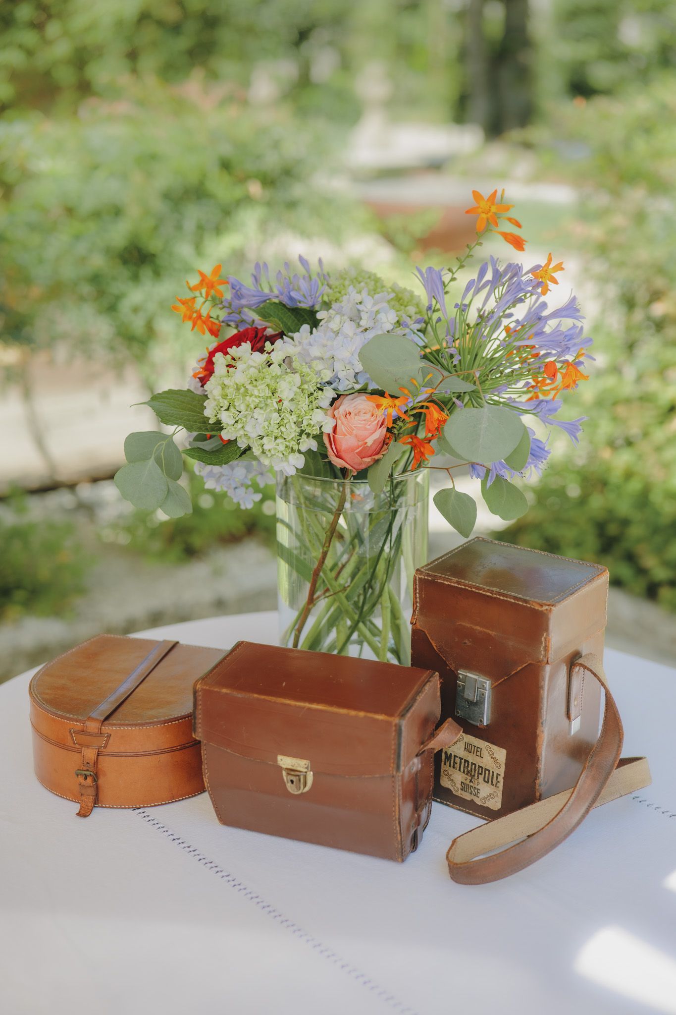 Rustic wooden boxes and vases with colorful wildflowers arranged on white table.
