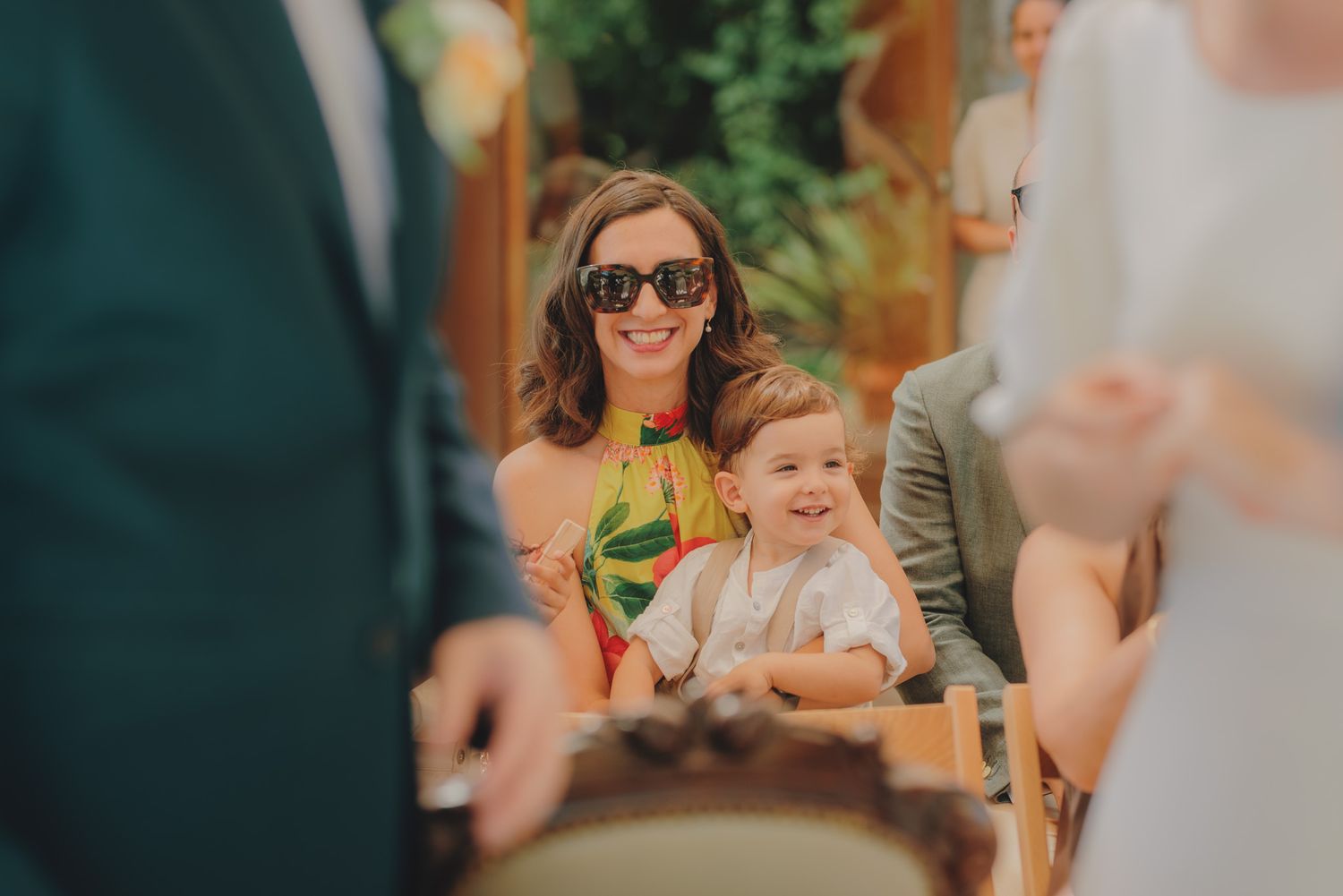Wedding guests enjoying a sunny outdoor reception with lush greenery in the background.