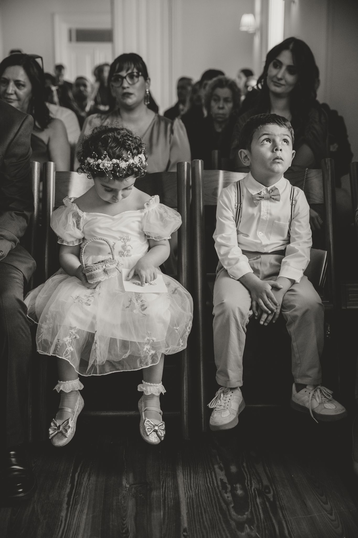 Black and white photo series showing children in formal white attire sitting on chairs at an event.