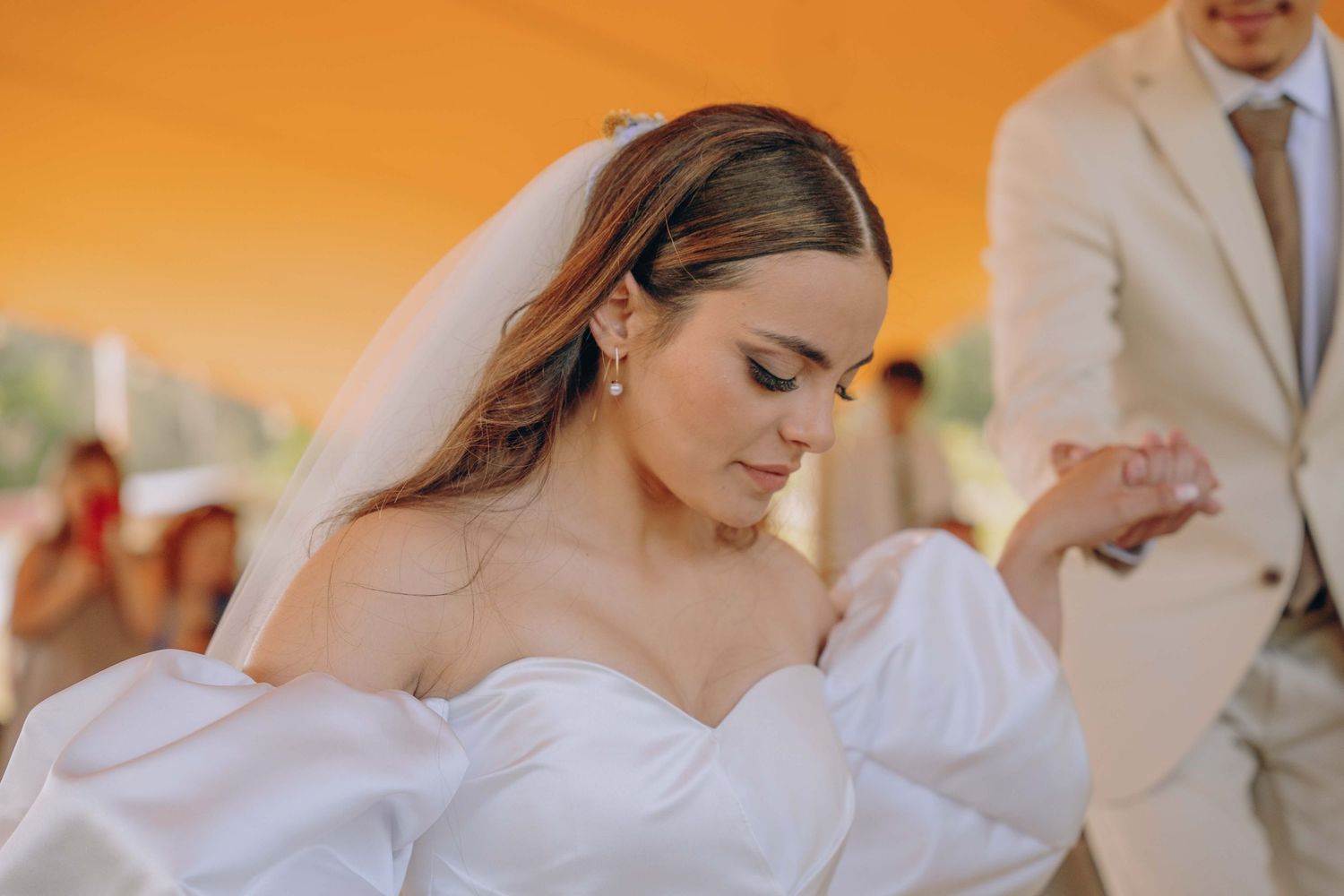 A wedding party in white and beige attire walks together outdoors during a sunset ceremony.