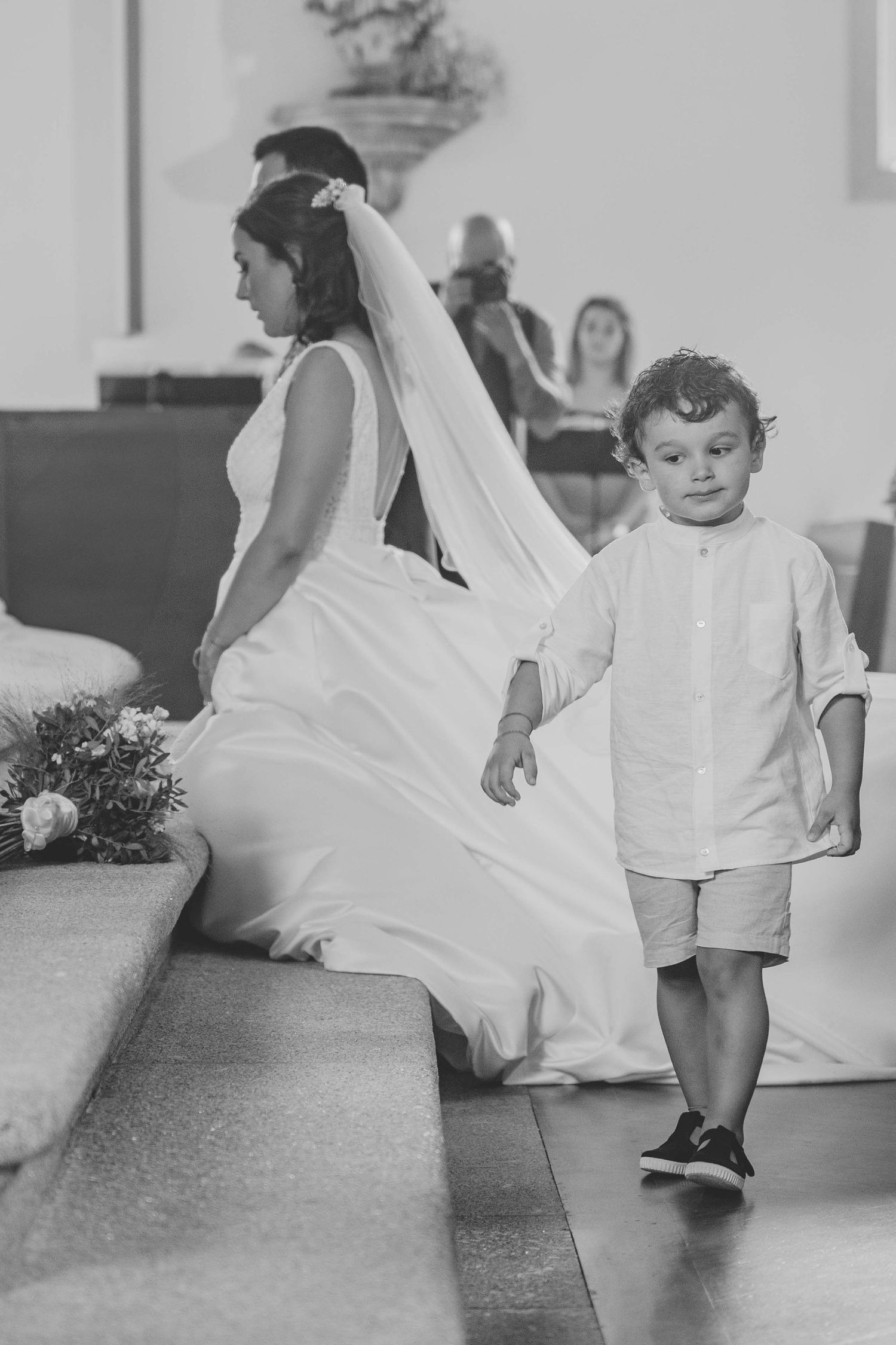 A black and white sequence showing a small child playing with a flowing white dress or fabric on a floor.