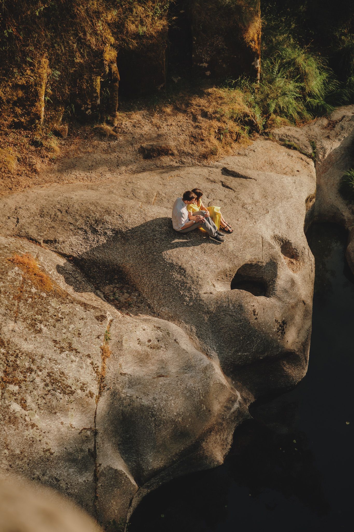 Large weathered rocks and boulders along a riverbank in warm evening light.