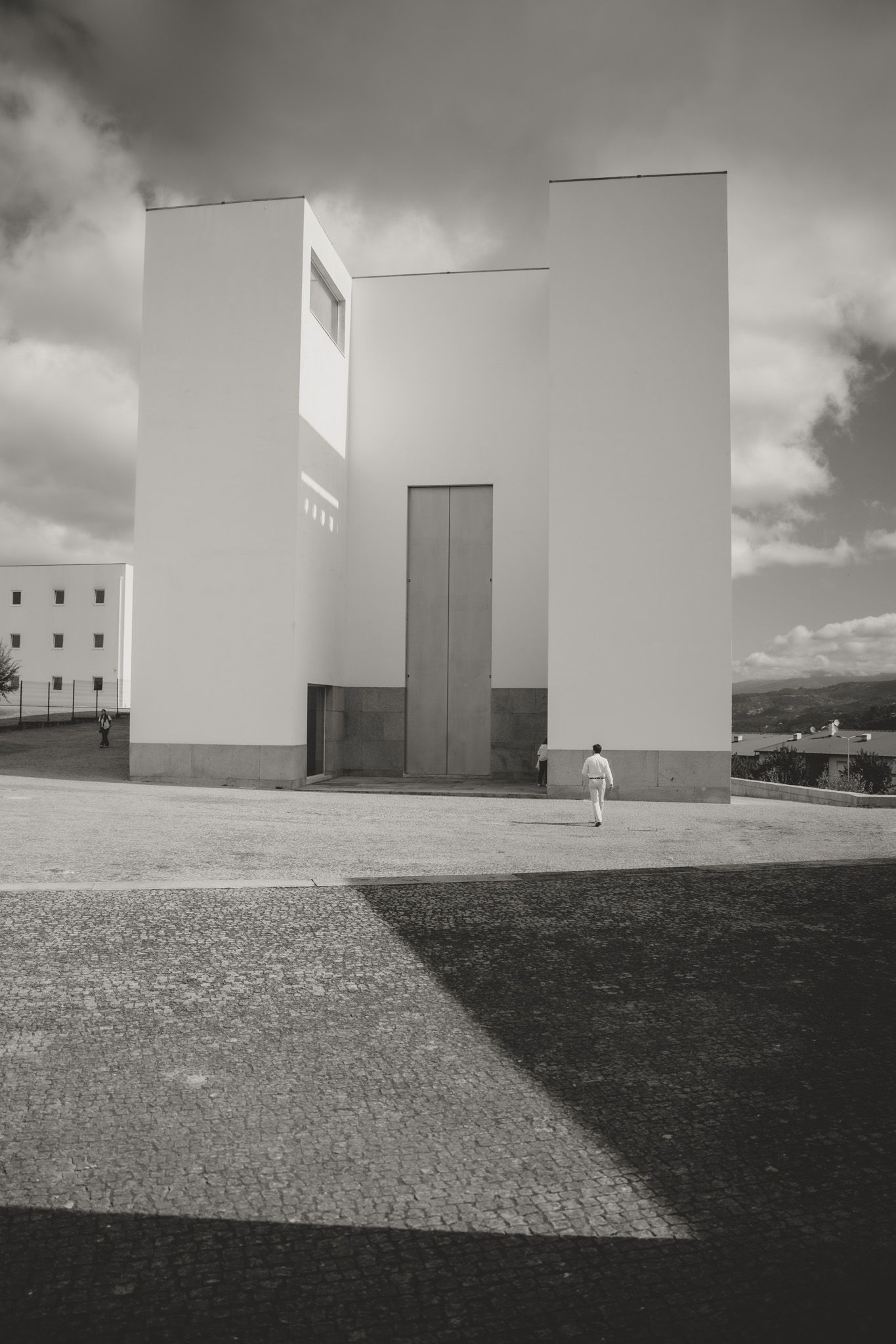 Minimalist architectural photographs of white geometric buildings against a cloudy sky.
