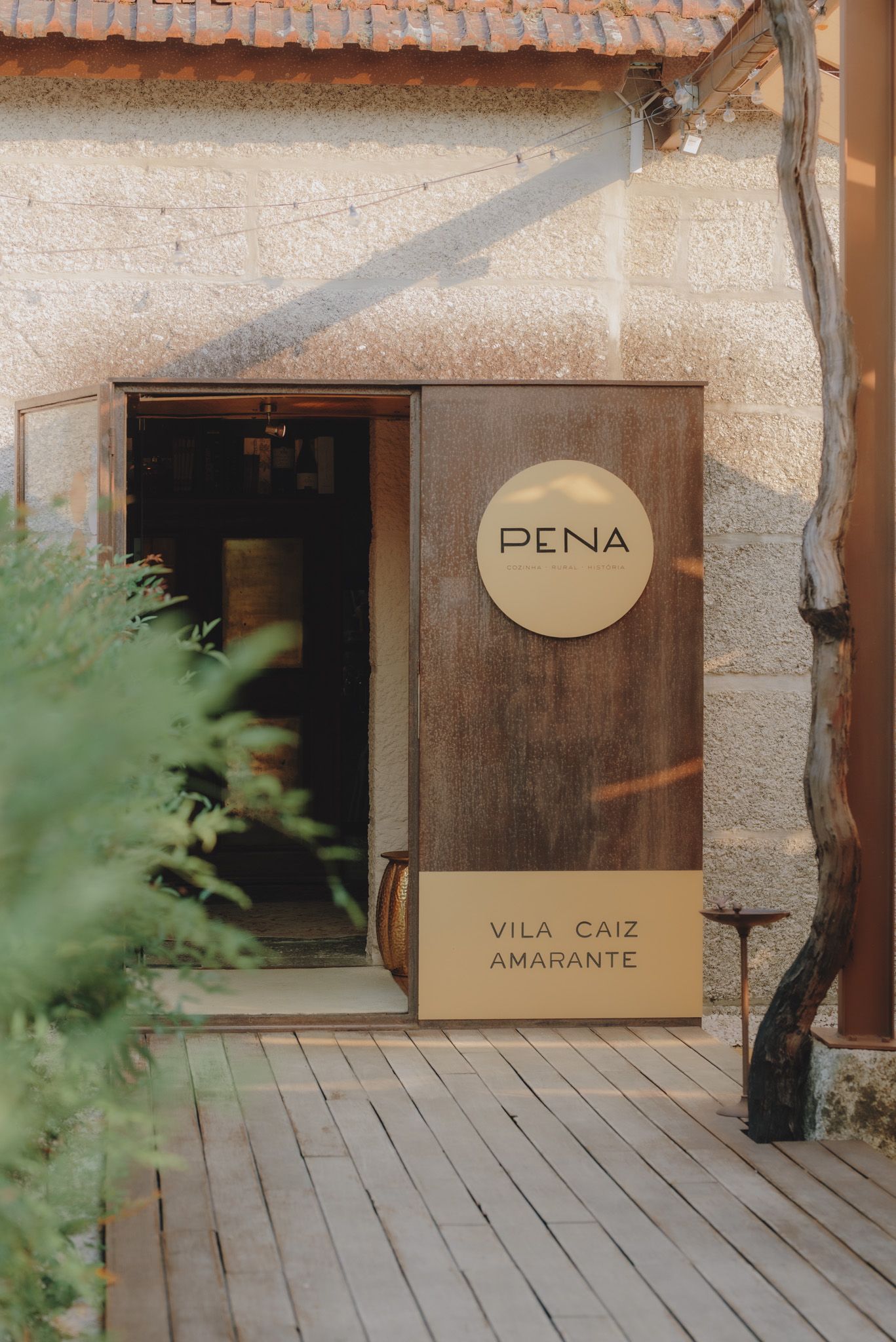 Rustic stone building entrance with 'Pena Vila Caiz Ambiente' signage.