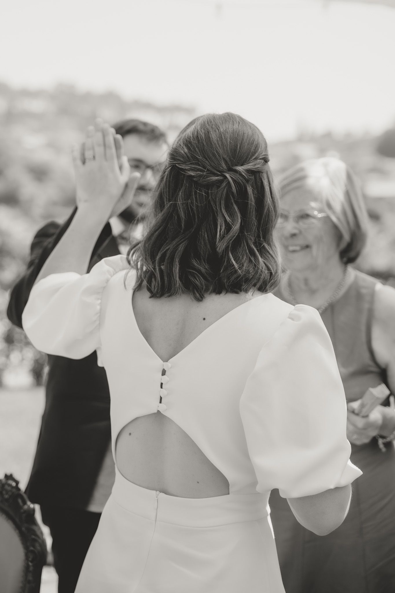 Bride in white dress dancing with raised arms at a wedding celebration.