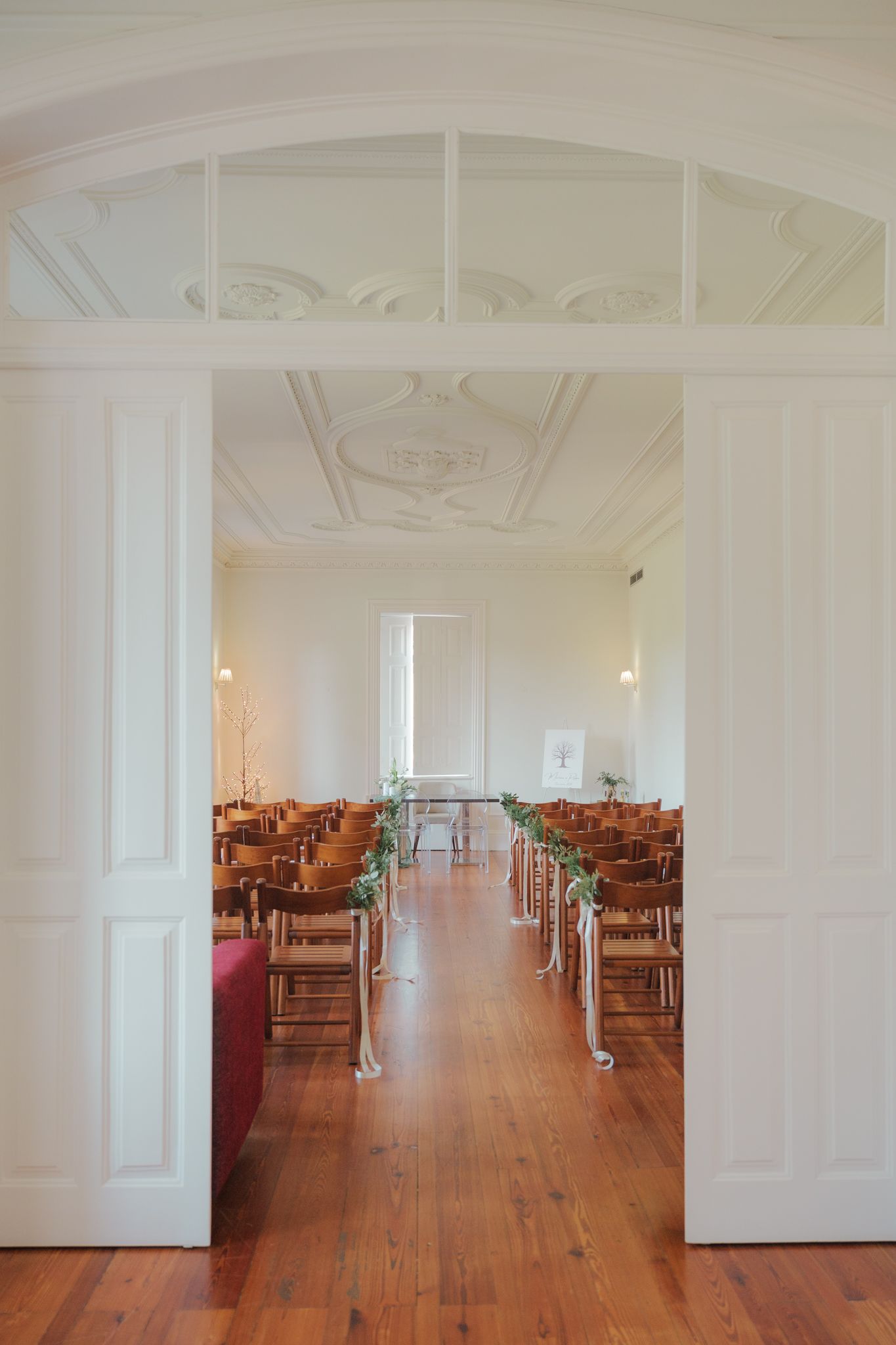 Elegant white interior hall with wooden floors and ornate ceiling details.