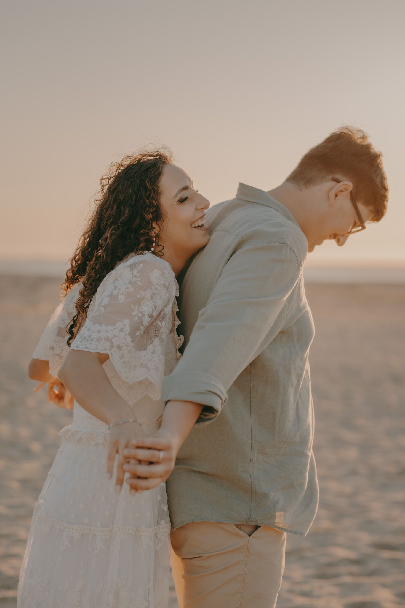 A couple shares an intimate moment on the beach during golden hour.