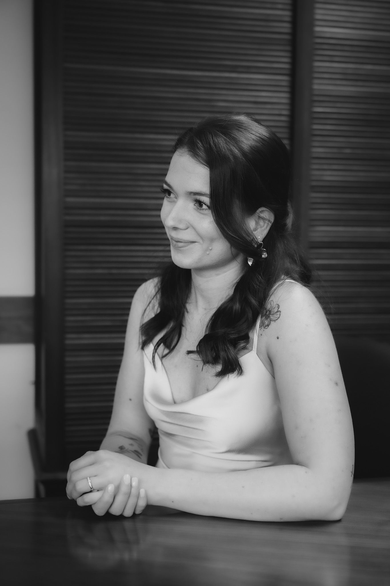 Black and white portrait of a person in a white top sitting at a table.