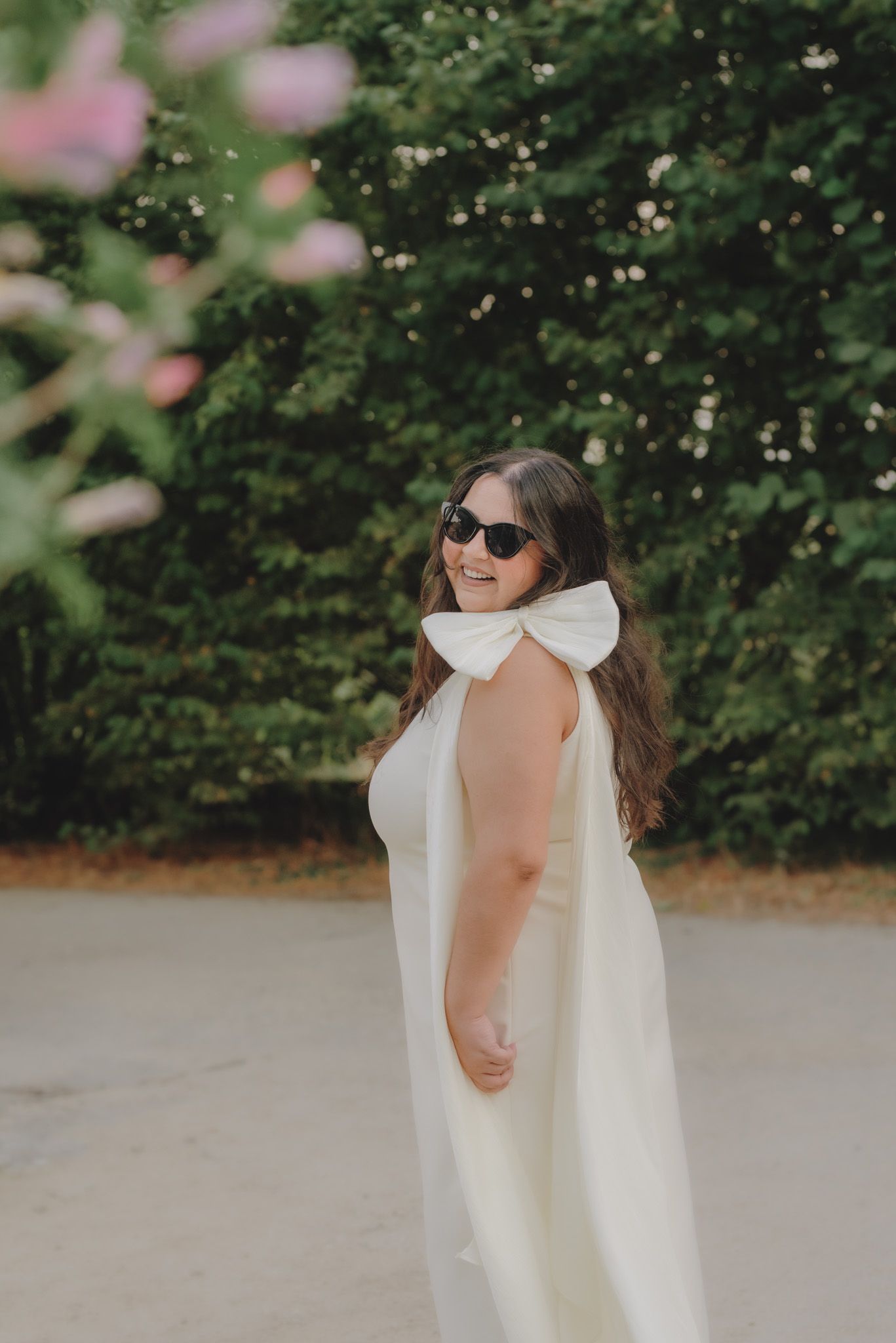 A series of artistic shots featuring a white dress with dramatic bow detail against lush greenery.