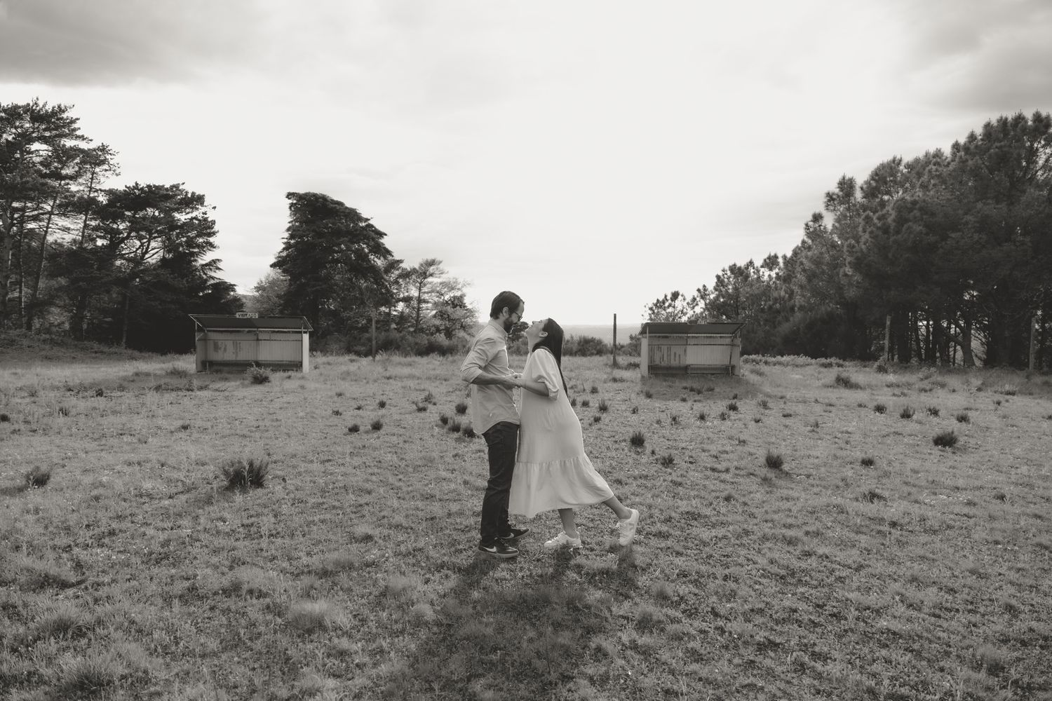 A black and white landscape photograph showing figures walking across an open field.