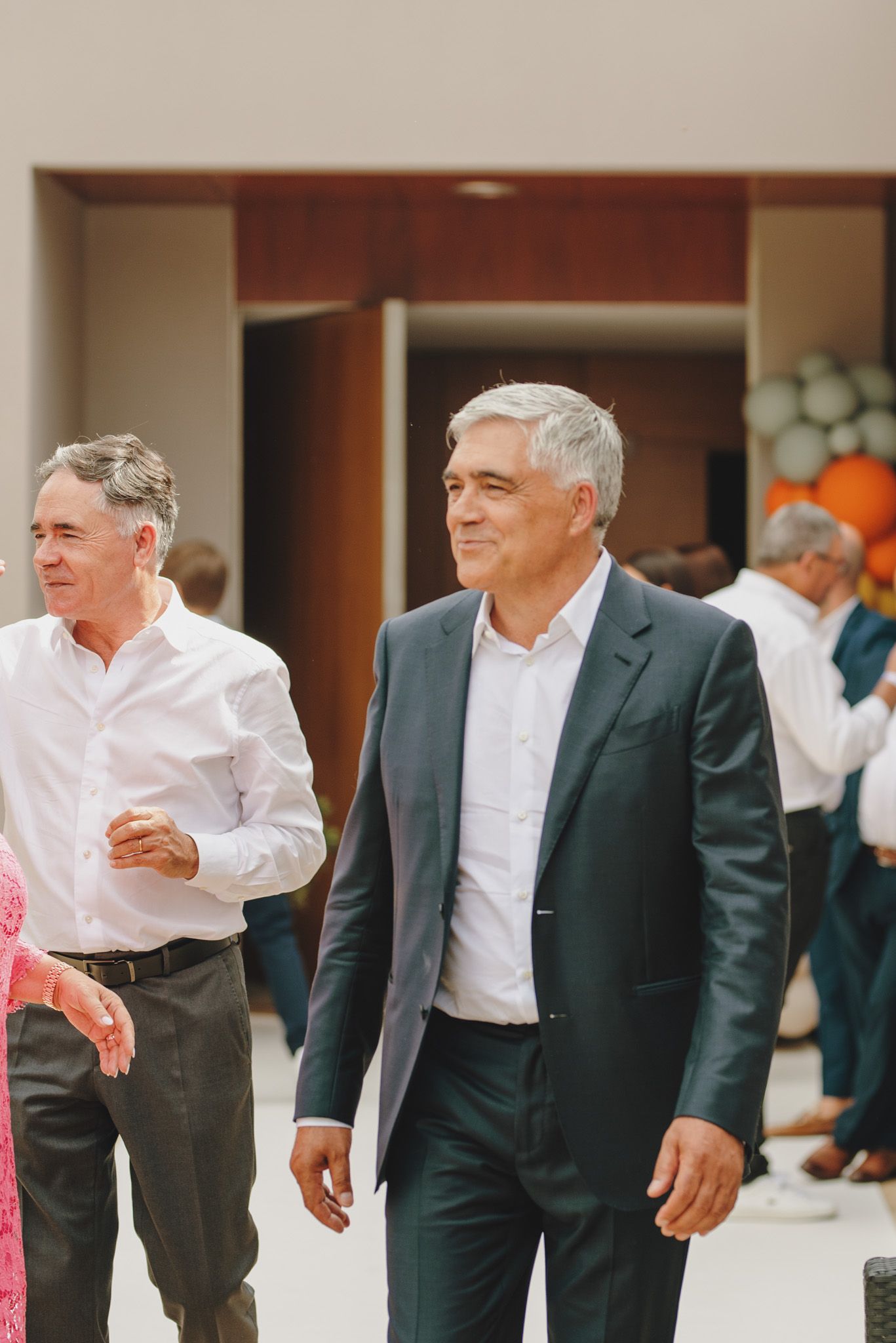 Men in formal suits and white shirts walking together at an event.