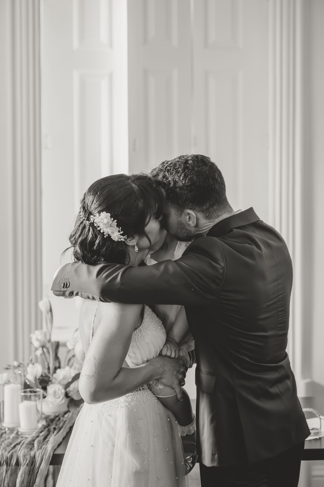 Intimate black and white wedding moment showing couple sharing a tender kiss during their celebration.