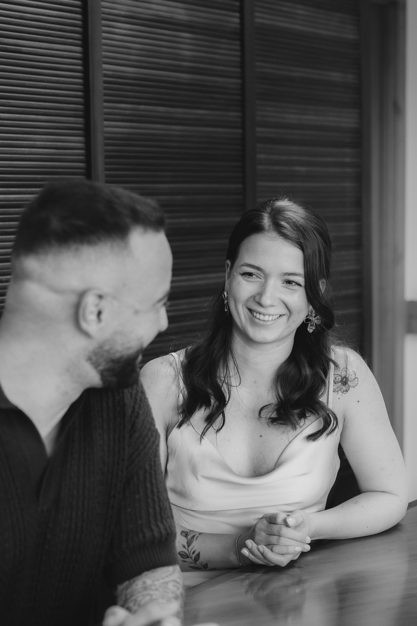 Black and white candid moment of a couple sharing laughter at a table.