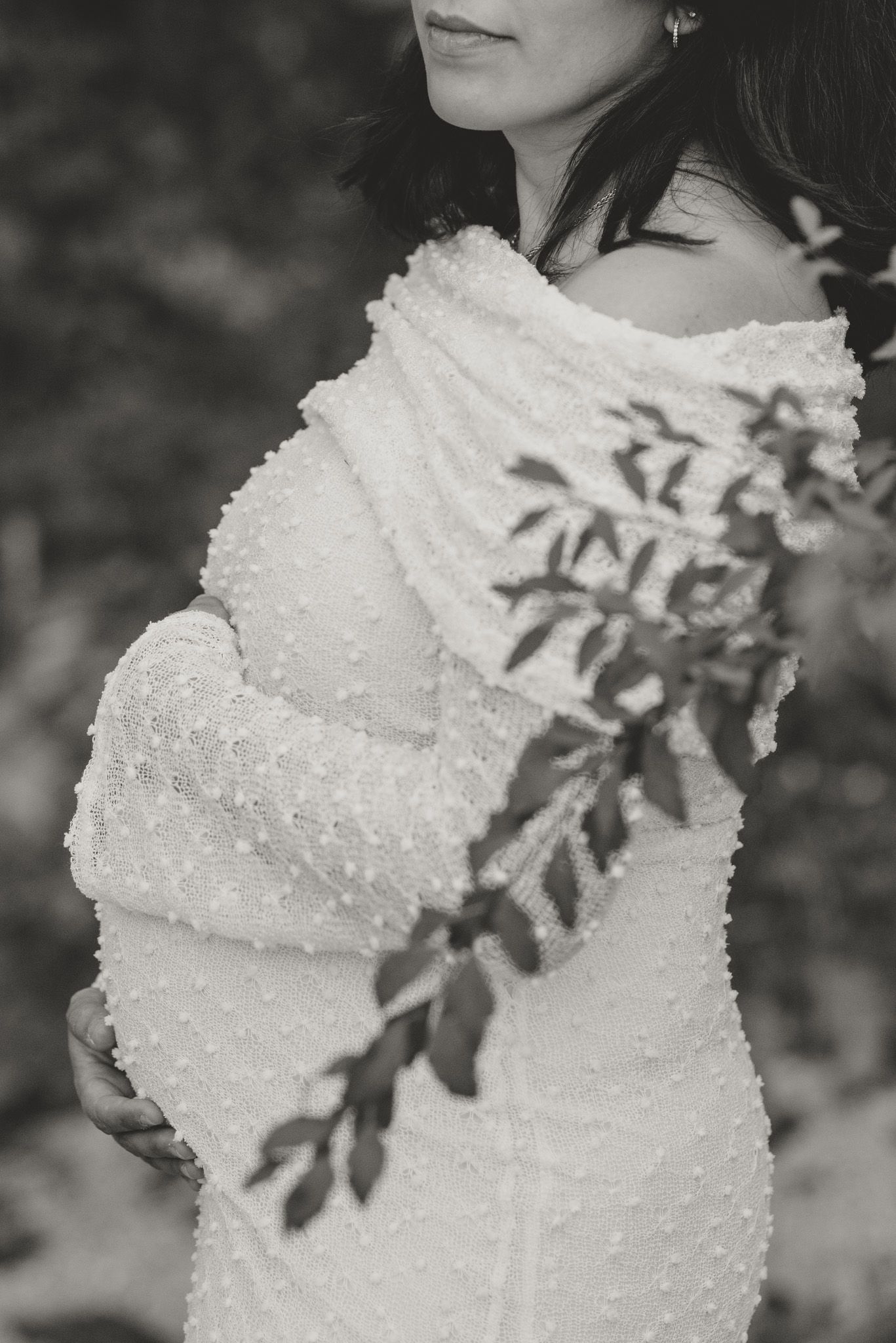 Monochrome side profile maternity photo with leaf shadows cast on a pearl-detailed dress.