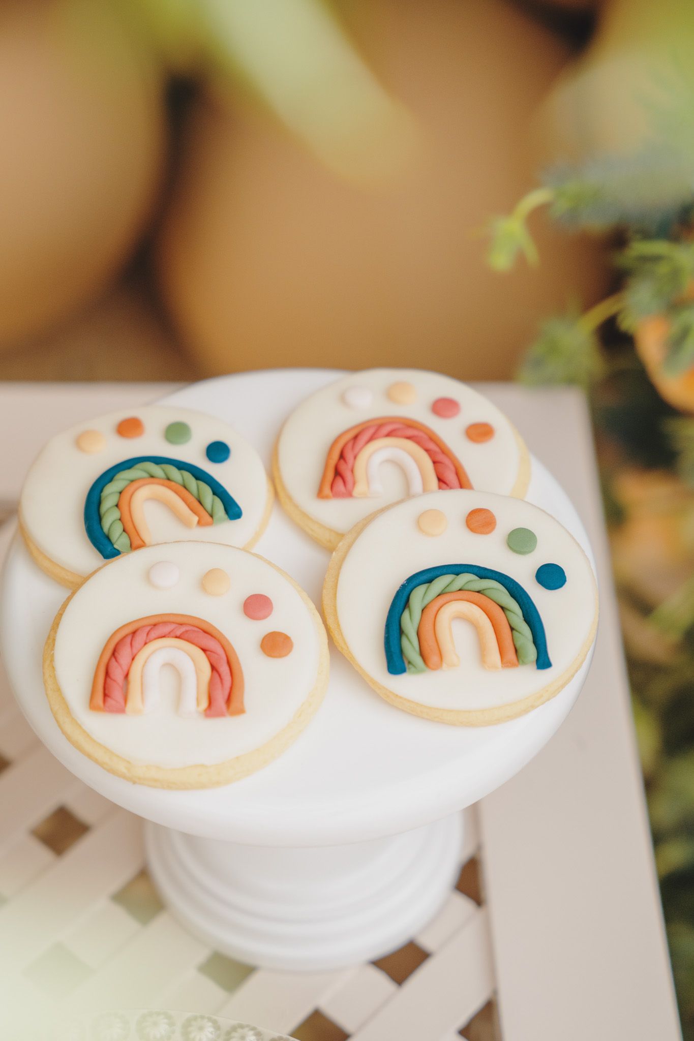White frosted cookies decorated with colorful rainbow designs displayed on serving plates.