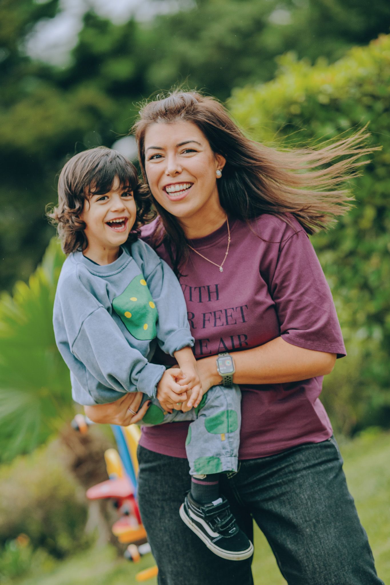 Two people share joyful moments outdoors while playing with a small globe toy in a green park setting.