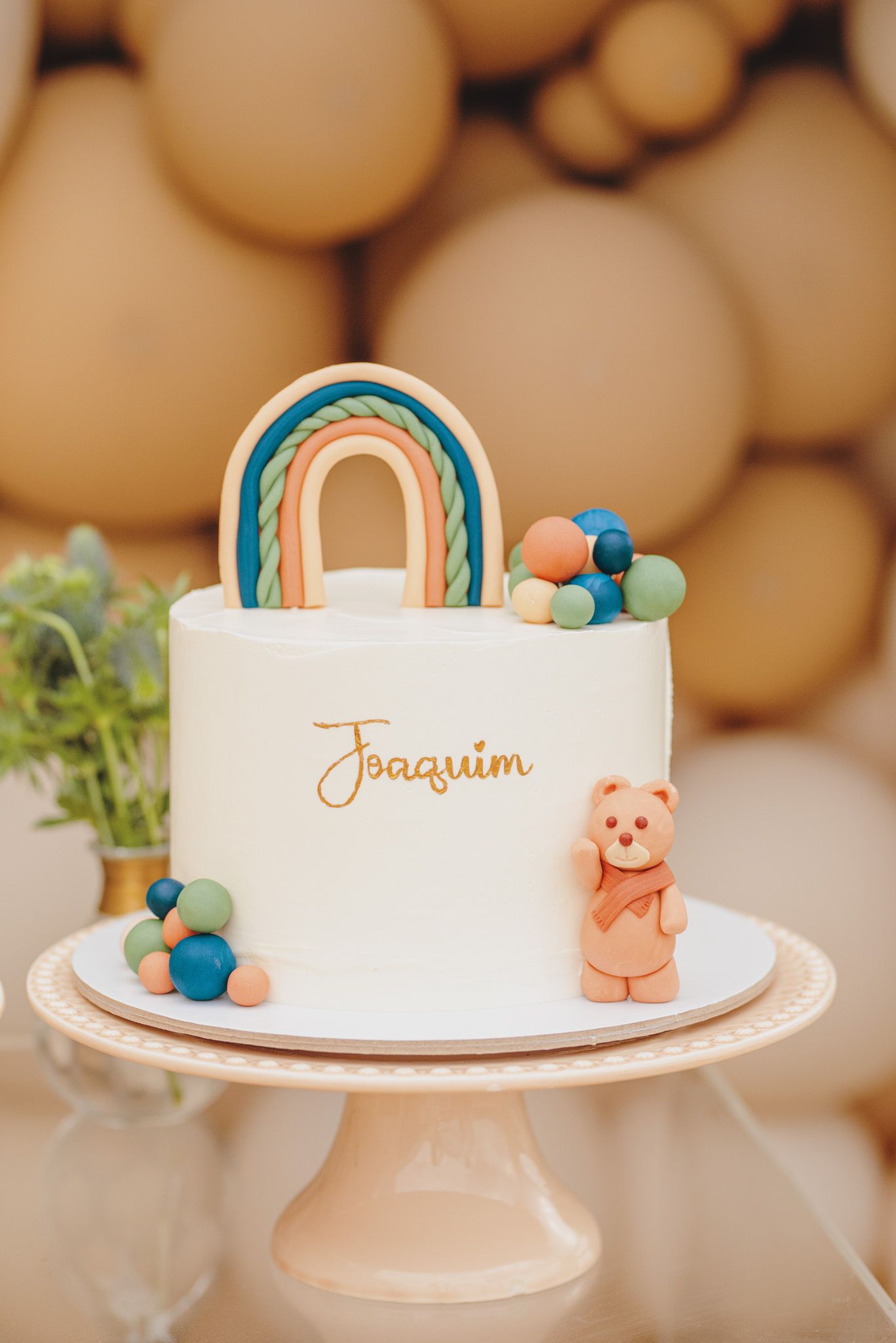 White celebration cake with blue and coral decorative elements displayed on a pedestal stand.