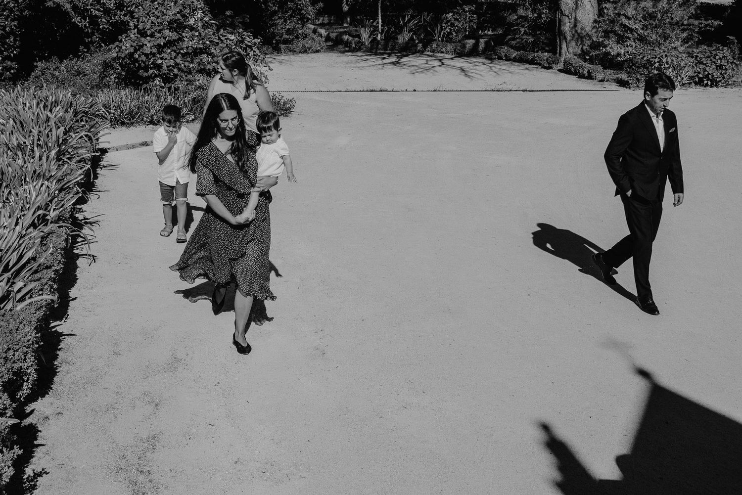 Black and white photo of people walking on a concrete path casting shadows in opposite directions.