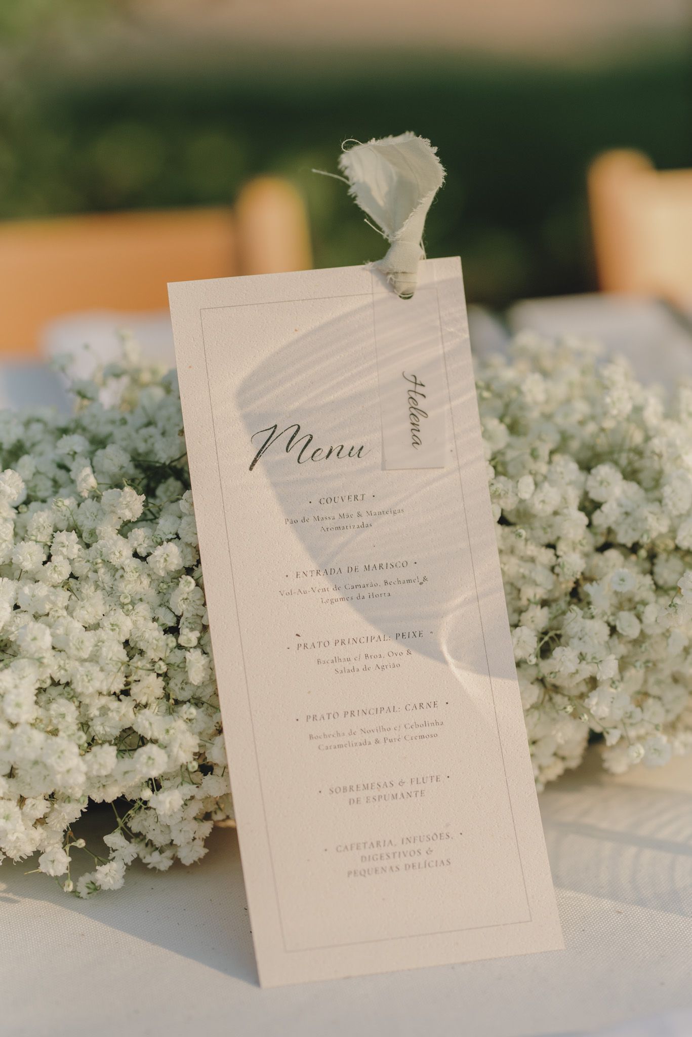 Elegant wedding menu cards displayed with delicate baby's breath flowers on a light colored surface.