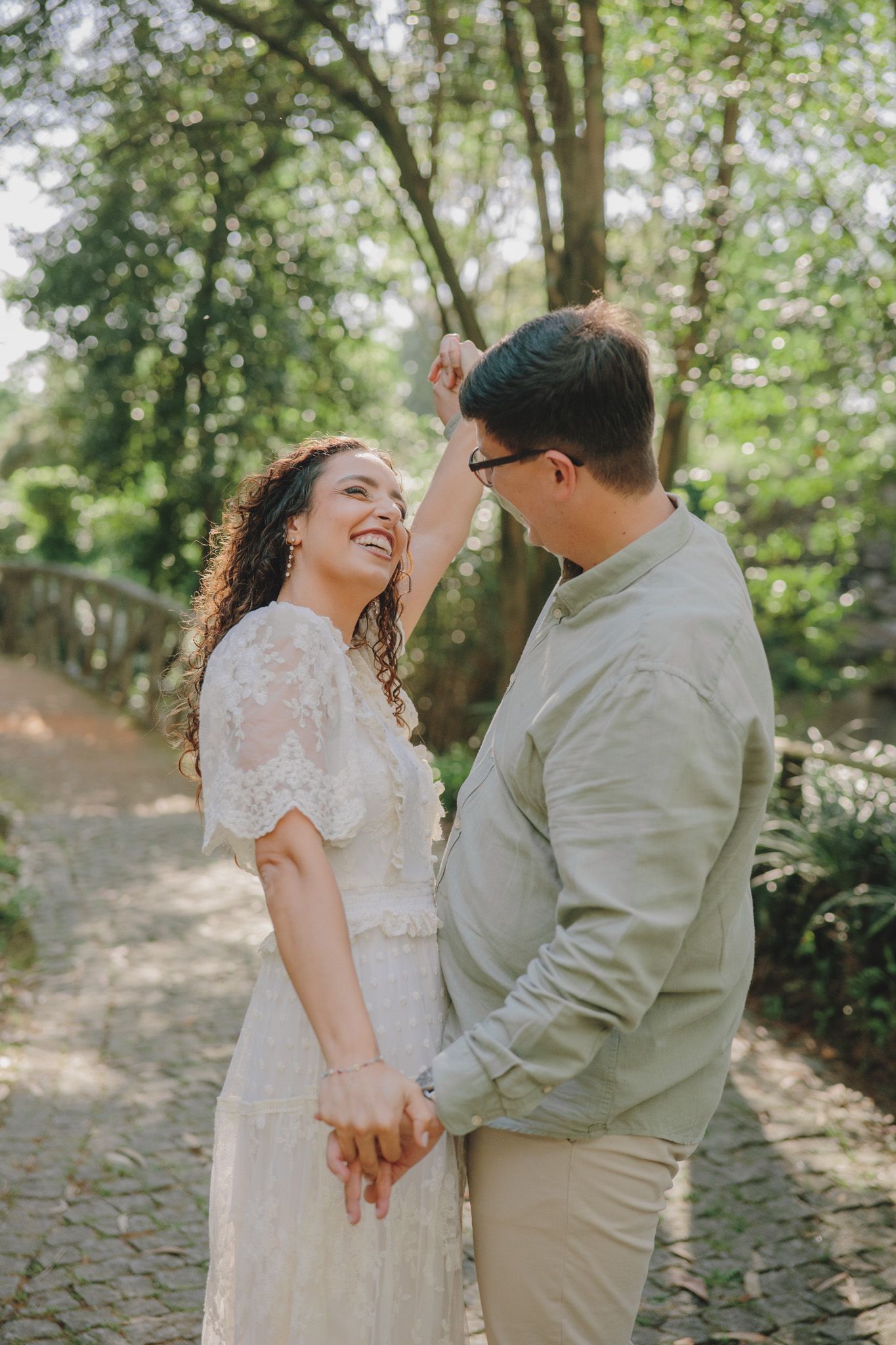 Couple sharing a joyful moment in a sunlit garden setting.