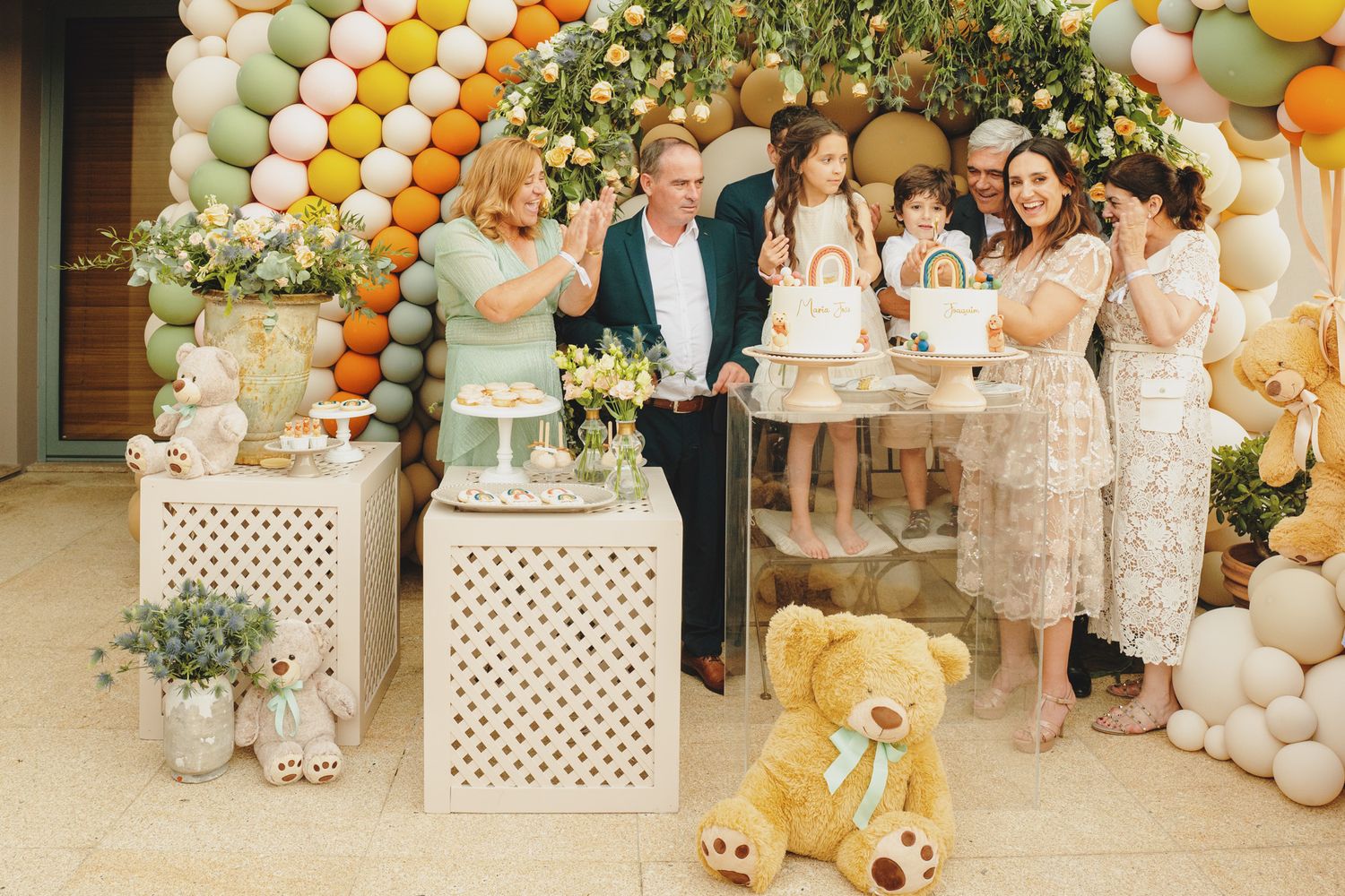 Elegant party setup with orange and white balloon arch and floral decorations.