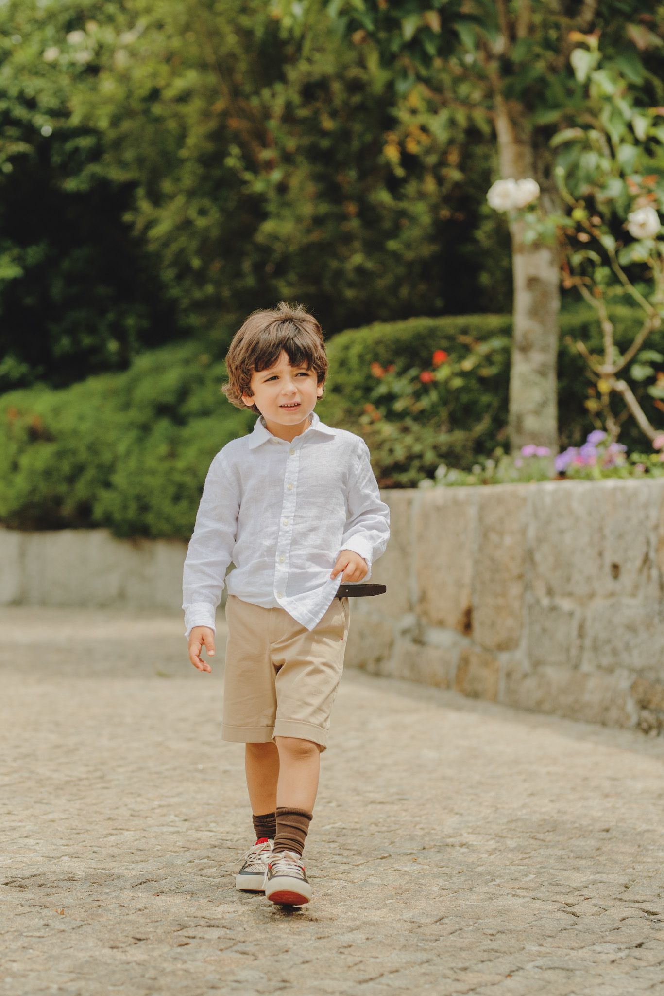 A child in khaki shorts and white shirt runs playfully on a stone pathway.