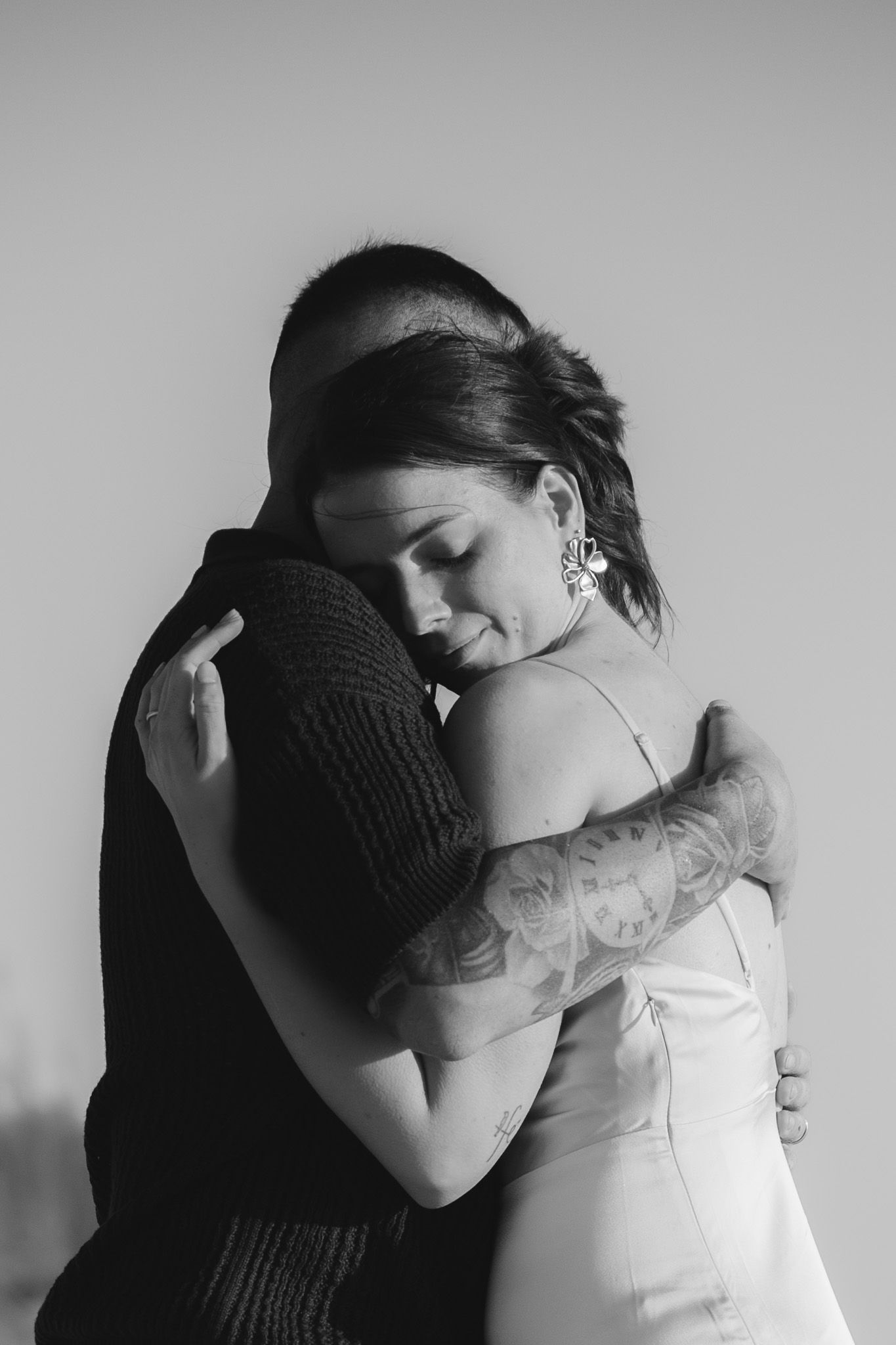 Intimate black and white portrait series showing emotional embrace against neutral background.