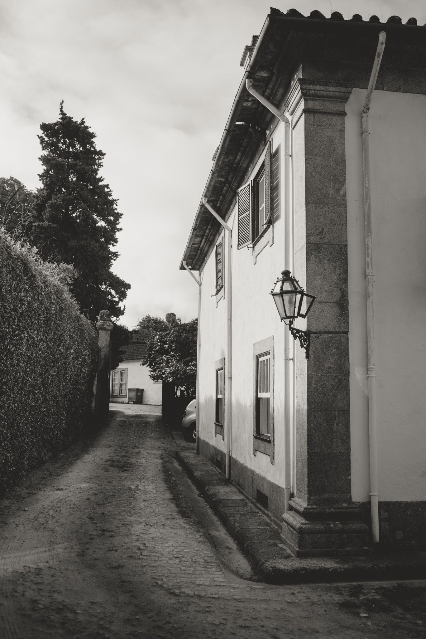 Black and white photograph of a narrow cobblestone street with traditional buildings.