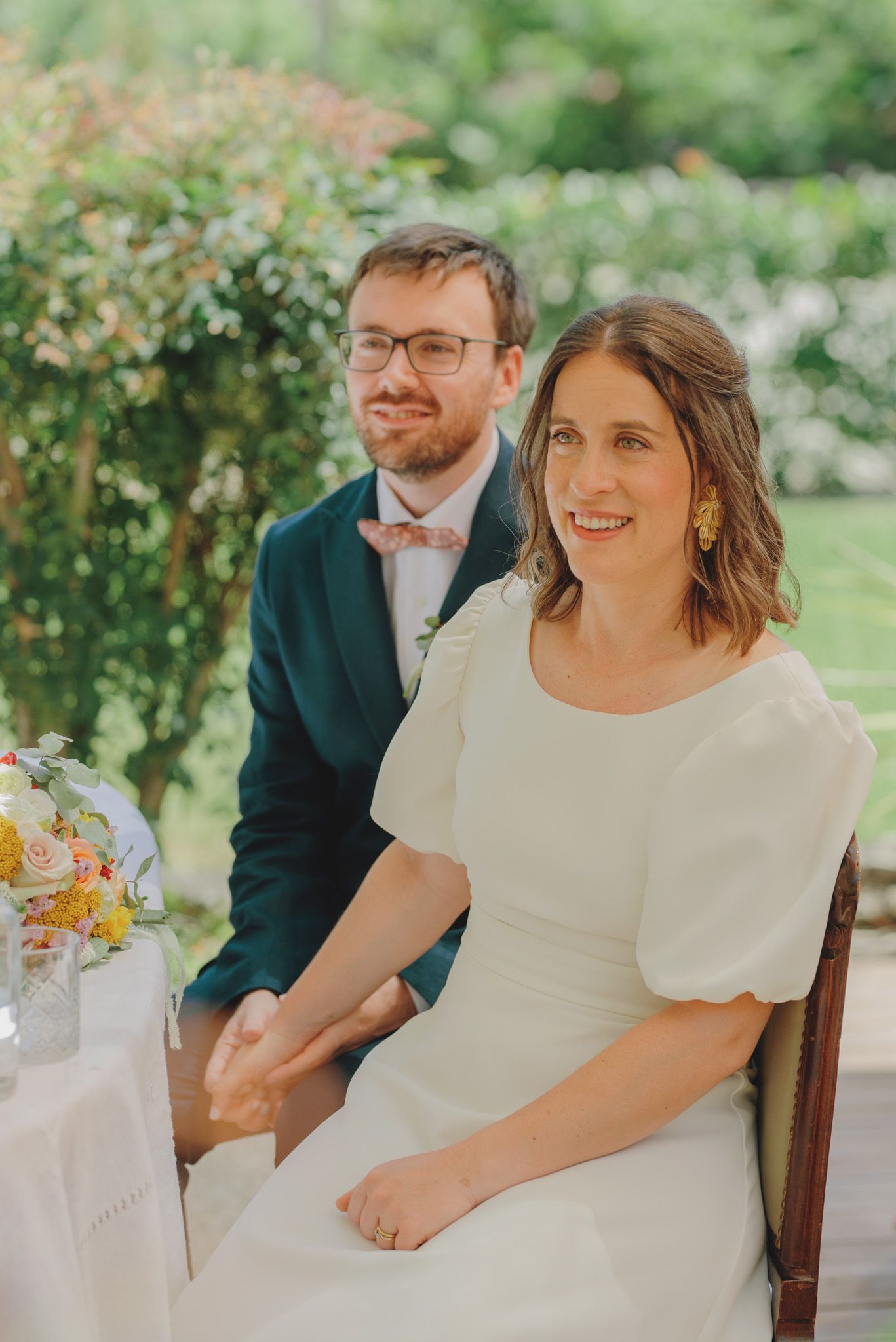 Couple shares joyful moments at an outdoor garden wedding reception.