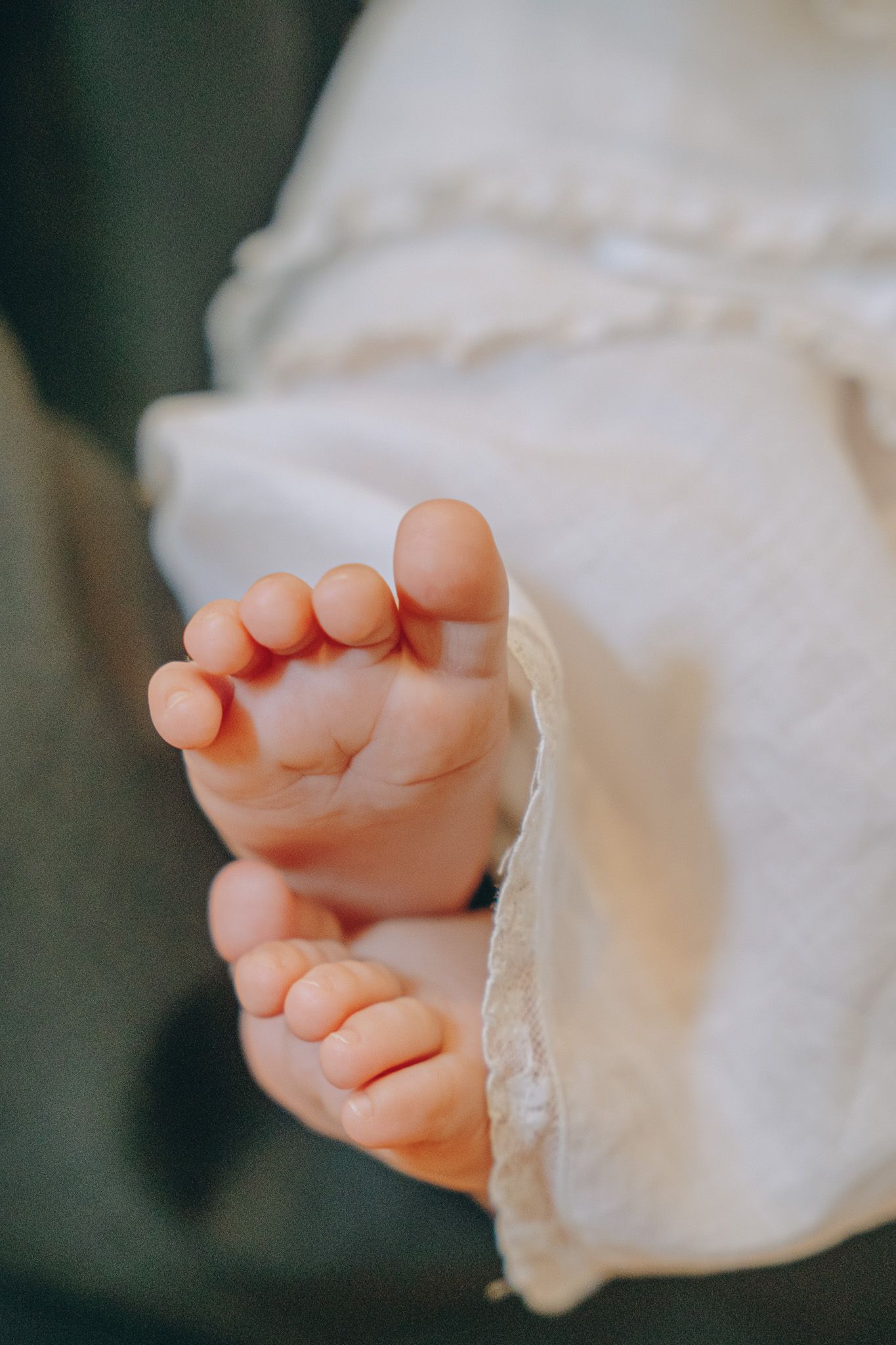 Close-up series of tiny baby feet wrapped in white fabric against dark background.
