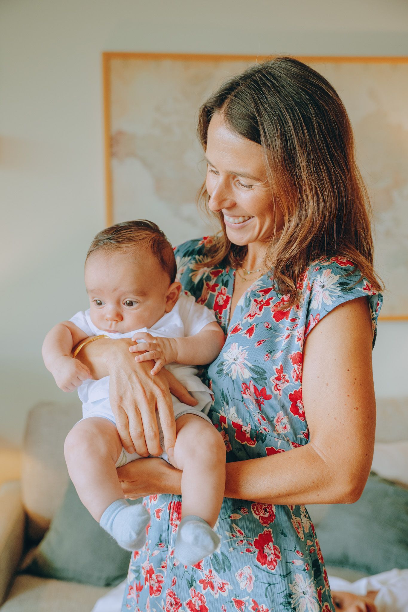 Series of tender moments between parent and baby in a bright room with floral dress.