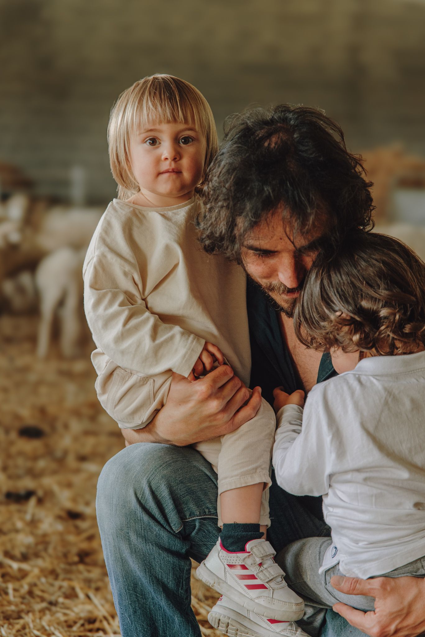 A tender outdoor family moment captured in warm autumn lighting with fallen leaves on the ground.