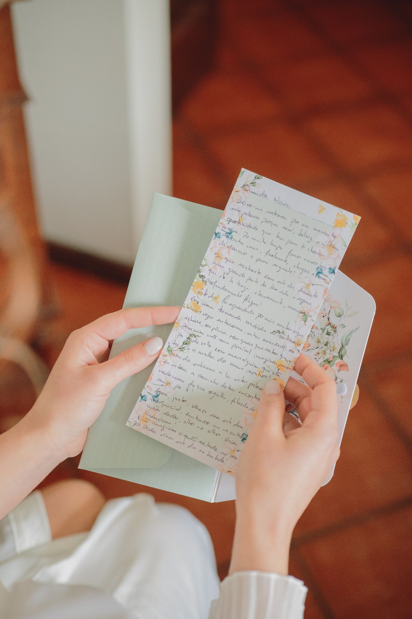 Hands holding handwritten letters with decorative floral details on the stationery paper.