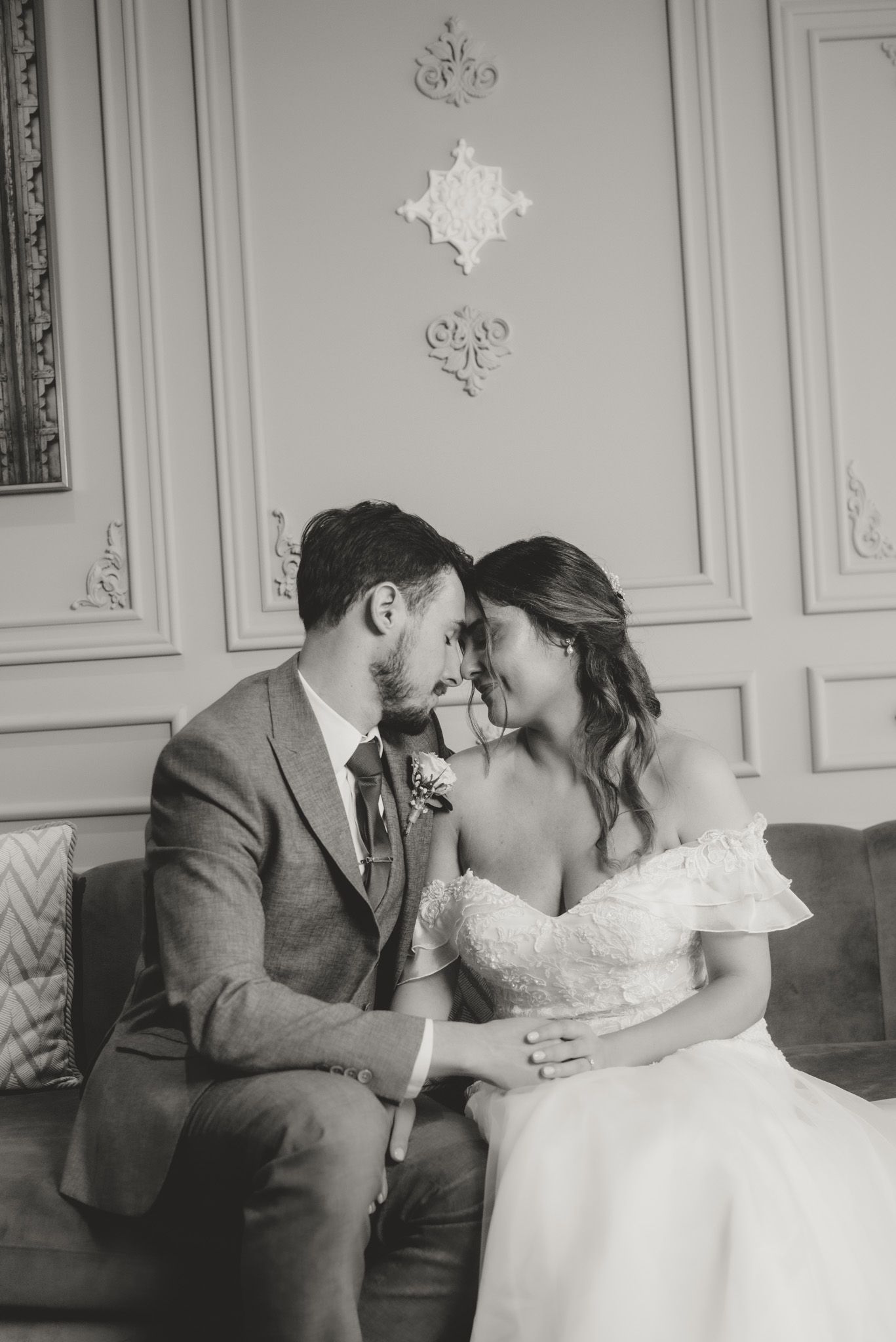 Intimate wedding moment captured in black and white in an ornate room.