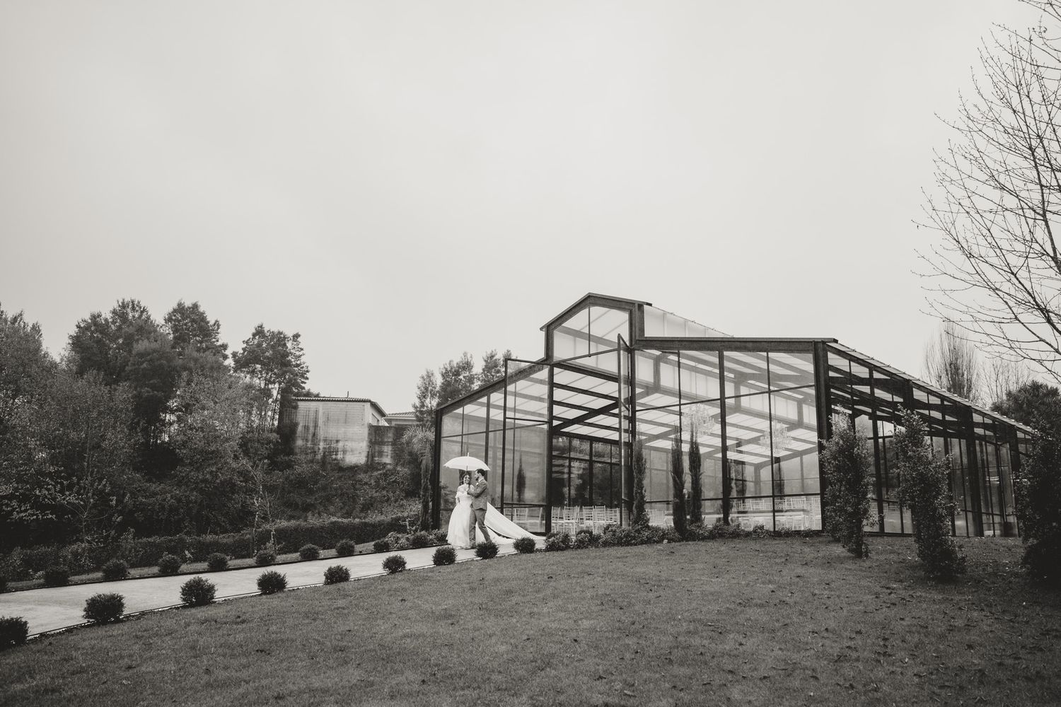 Exterior view of a rustic barn or greenhouse structure with glass panels and wooden beams.